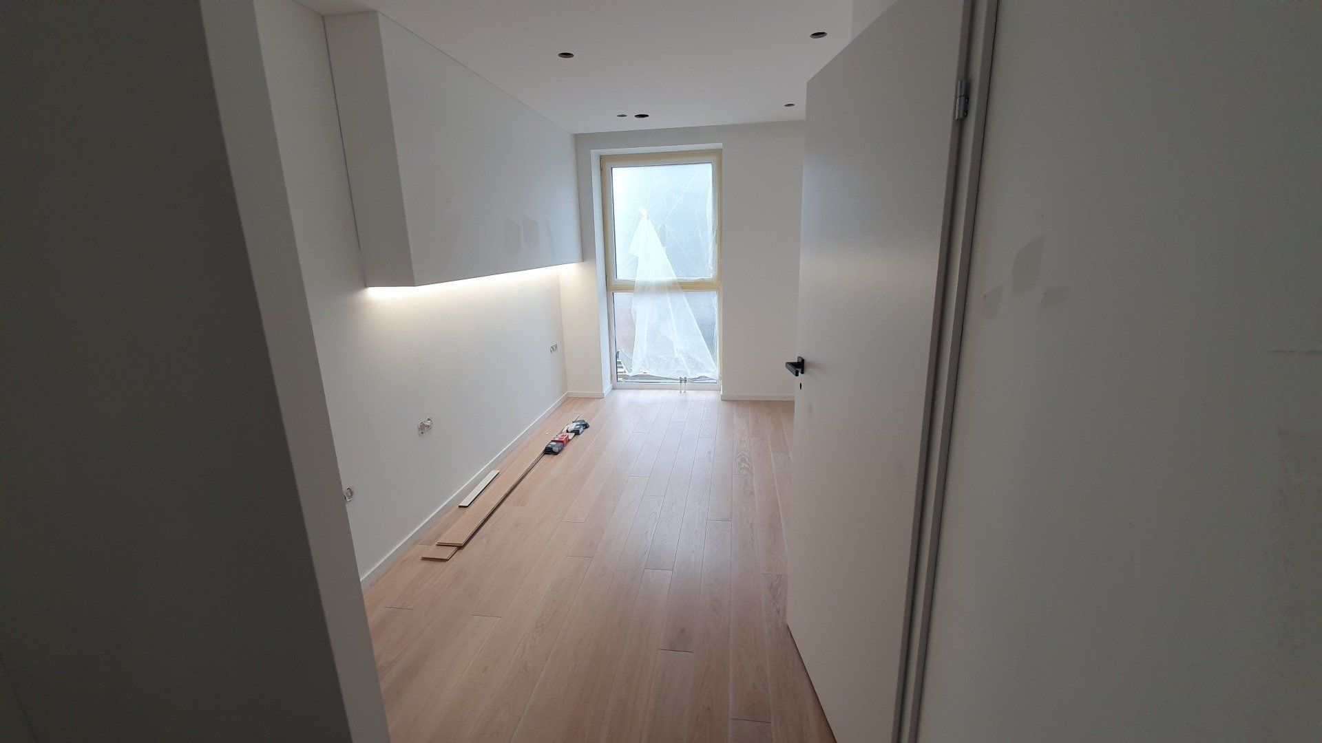 Tuščias kambarys su medinėmis grindimis ir baltomis sienomis