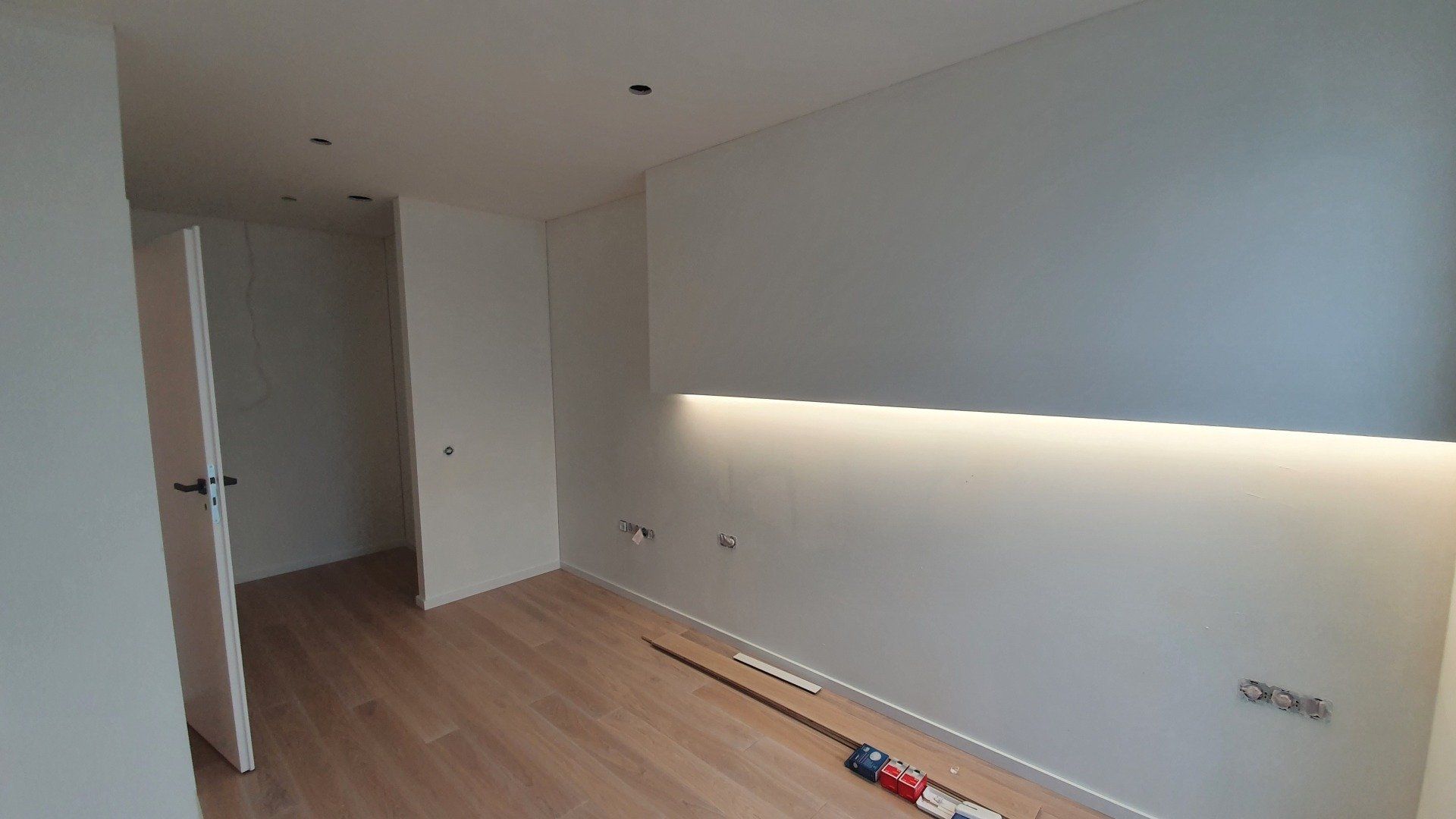 Tuščias kambarys su medinėmis grindimis ir baltomis sienomis