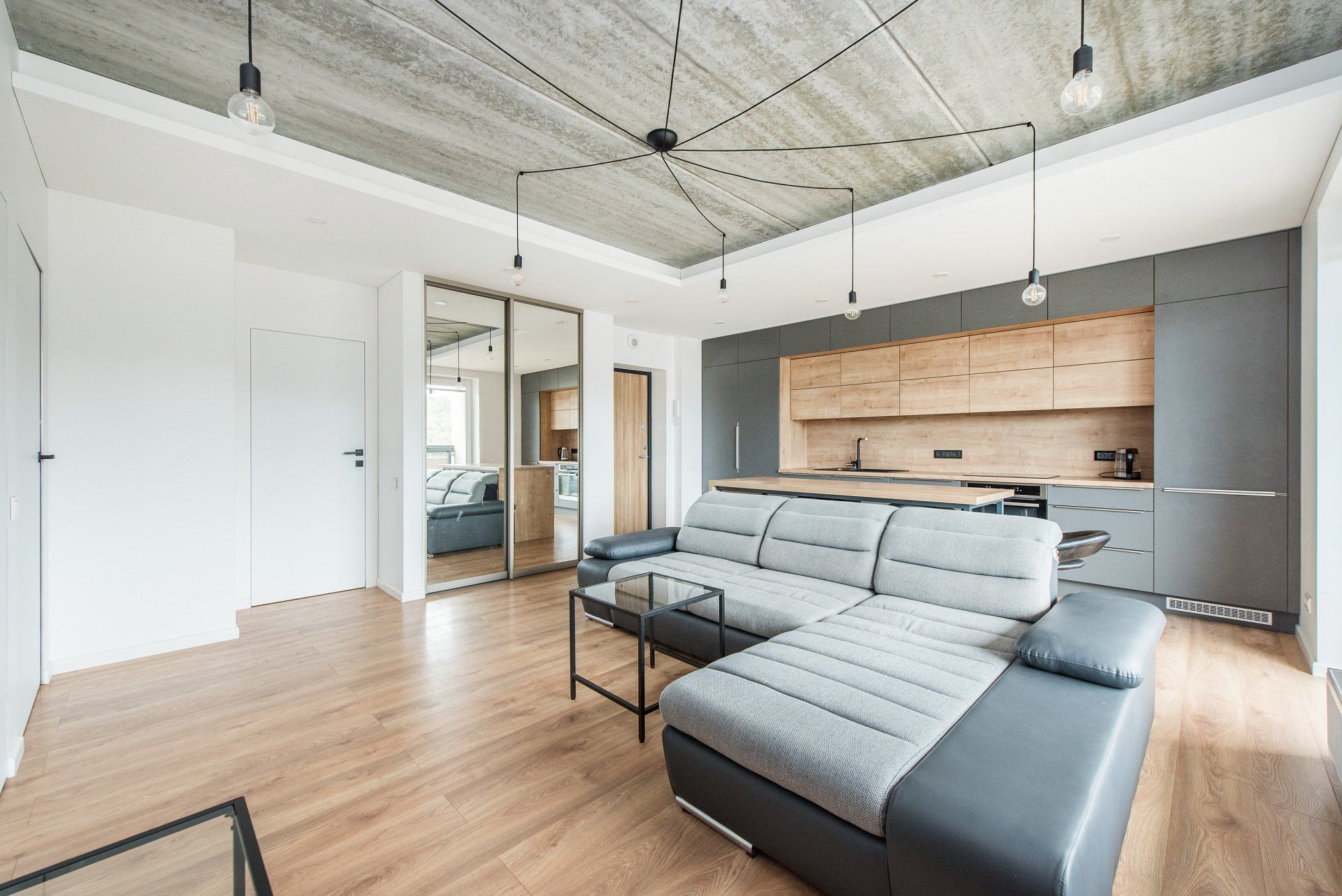 Svetainė su sofa, kavos staliuku ir stumdomomis stiklinėmis durimis.