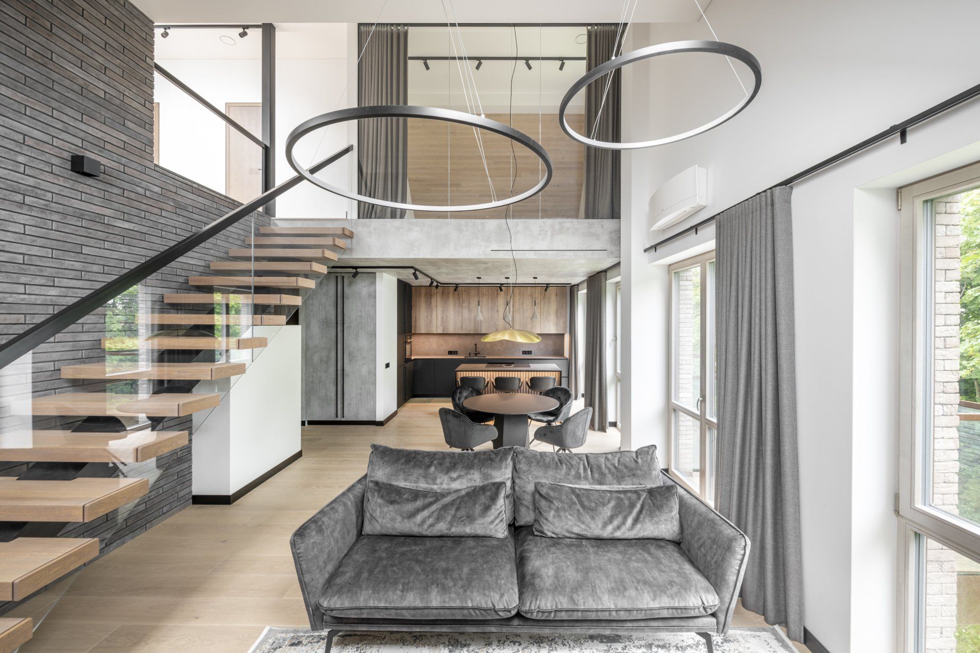 Svetainė su sofa, stalu, kėdėmis ir laiptais.