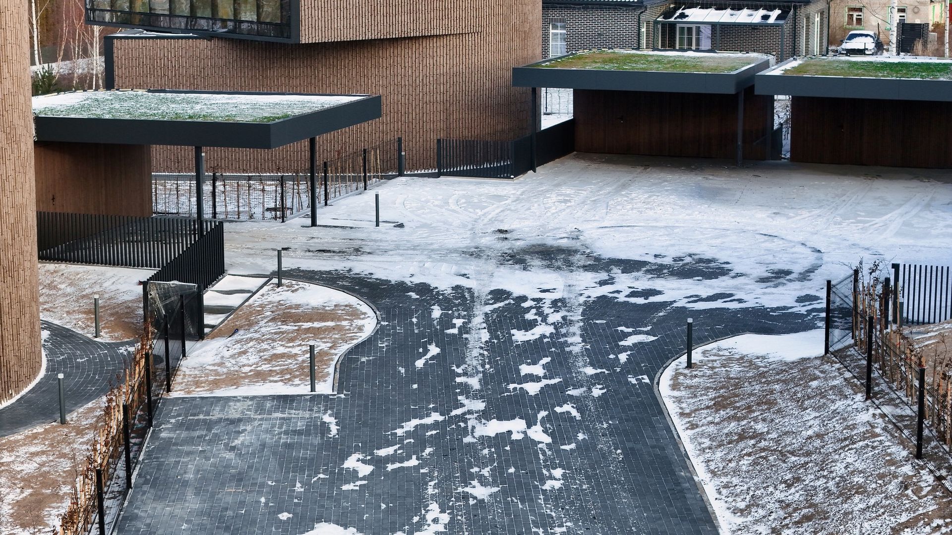 Snieguotas įvažiavimas, vedantis į pastatą su žaliu stogu