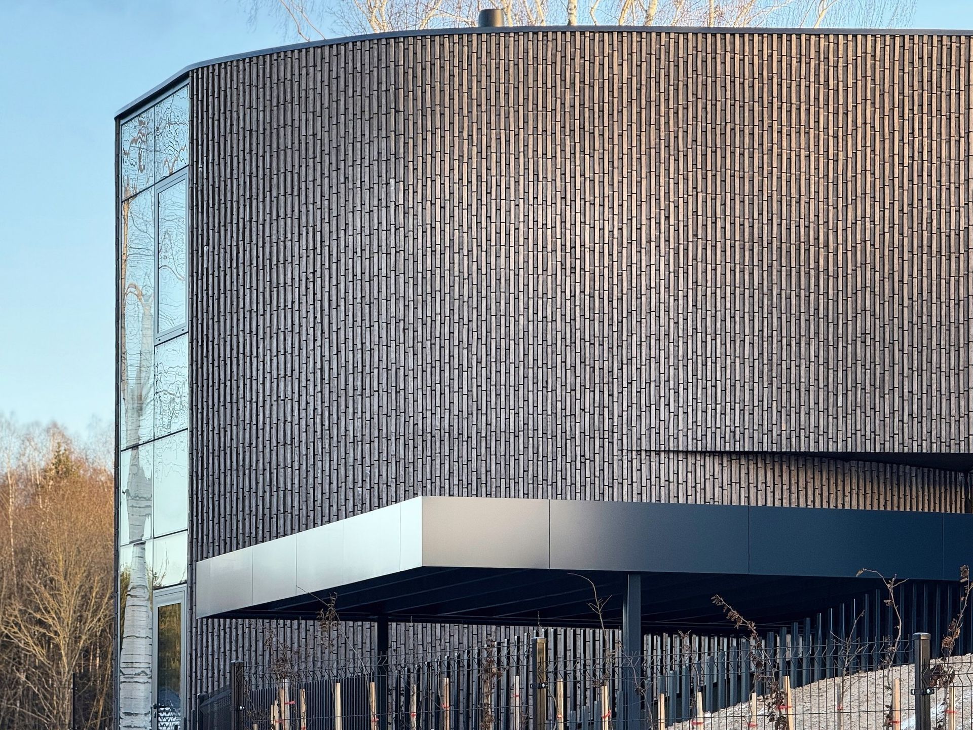 Didelis pastatas su mediniu ir stikliniu fasadais.