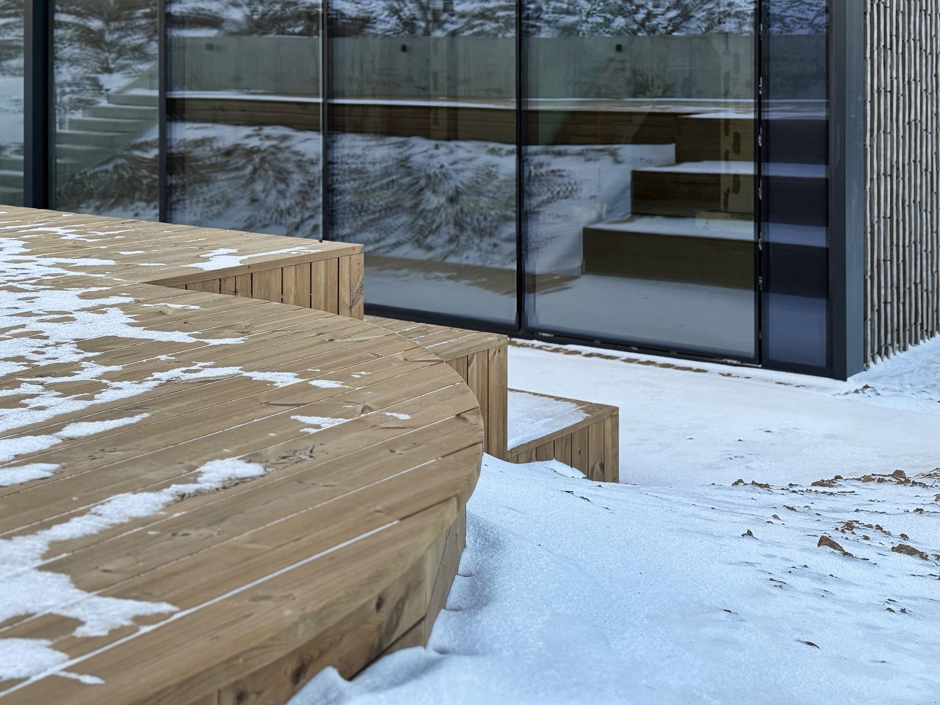 Medinė terasa su sniegu priešais pastatą
