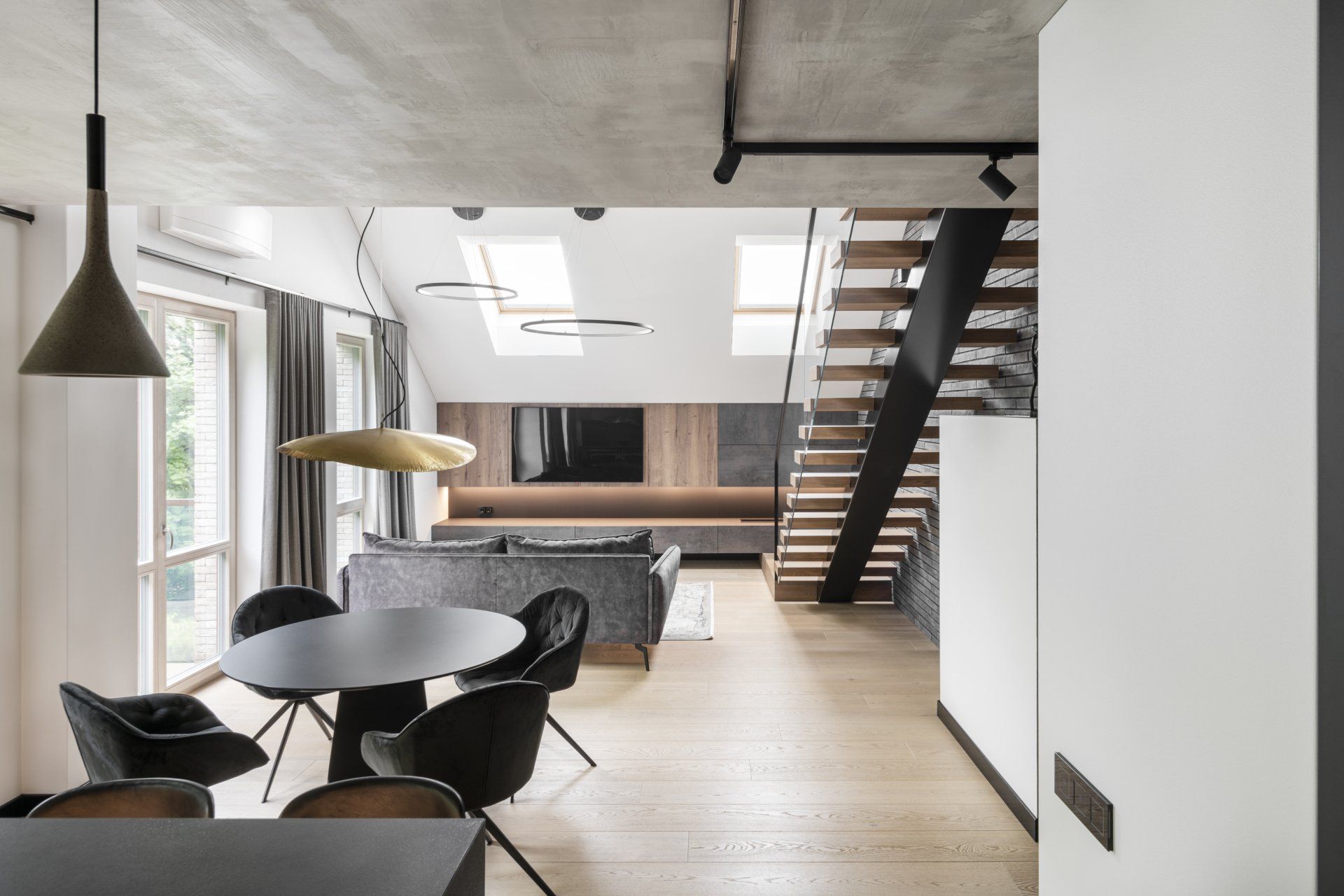 Svetainė su stalu, kėdėmis ir laiptais.