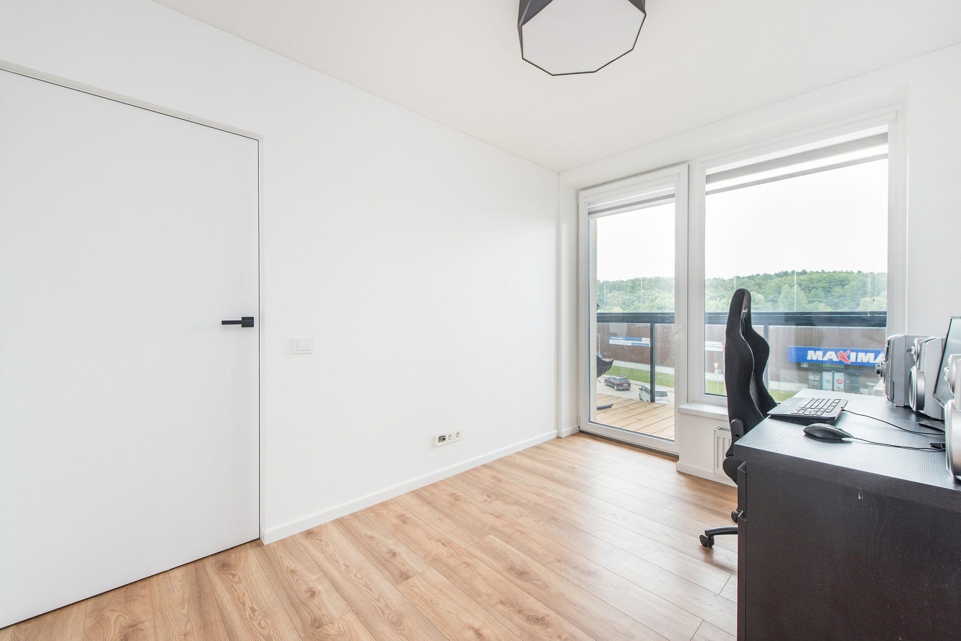 Kambarys su rašomuoju stalu, kėde ir balkonu.