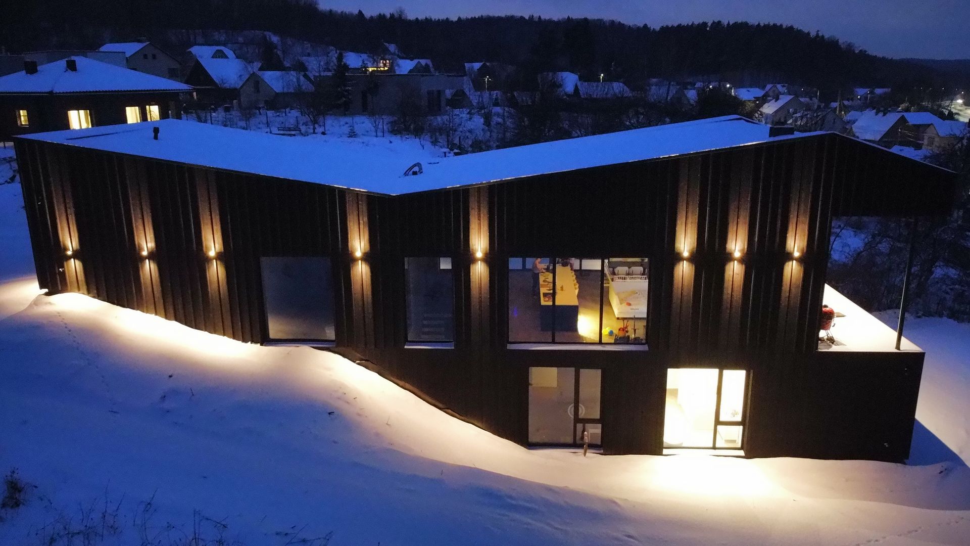 Namo sniege vaizdas iš oro naktį.