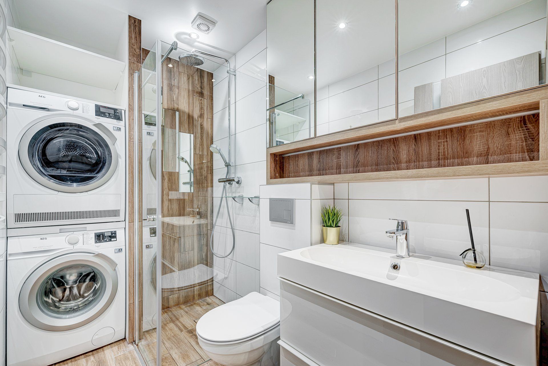 Vonios kambarys su skalbimo mašina ir džiovykle, sudėtomis viena ant kitos.