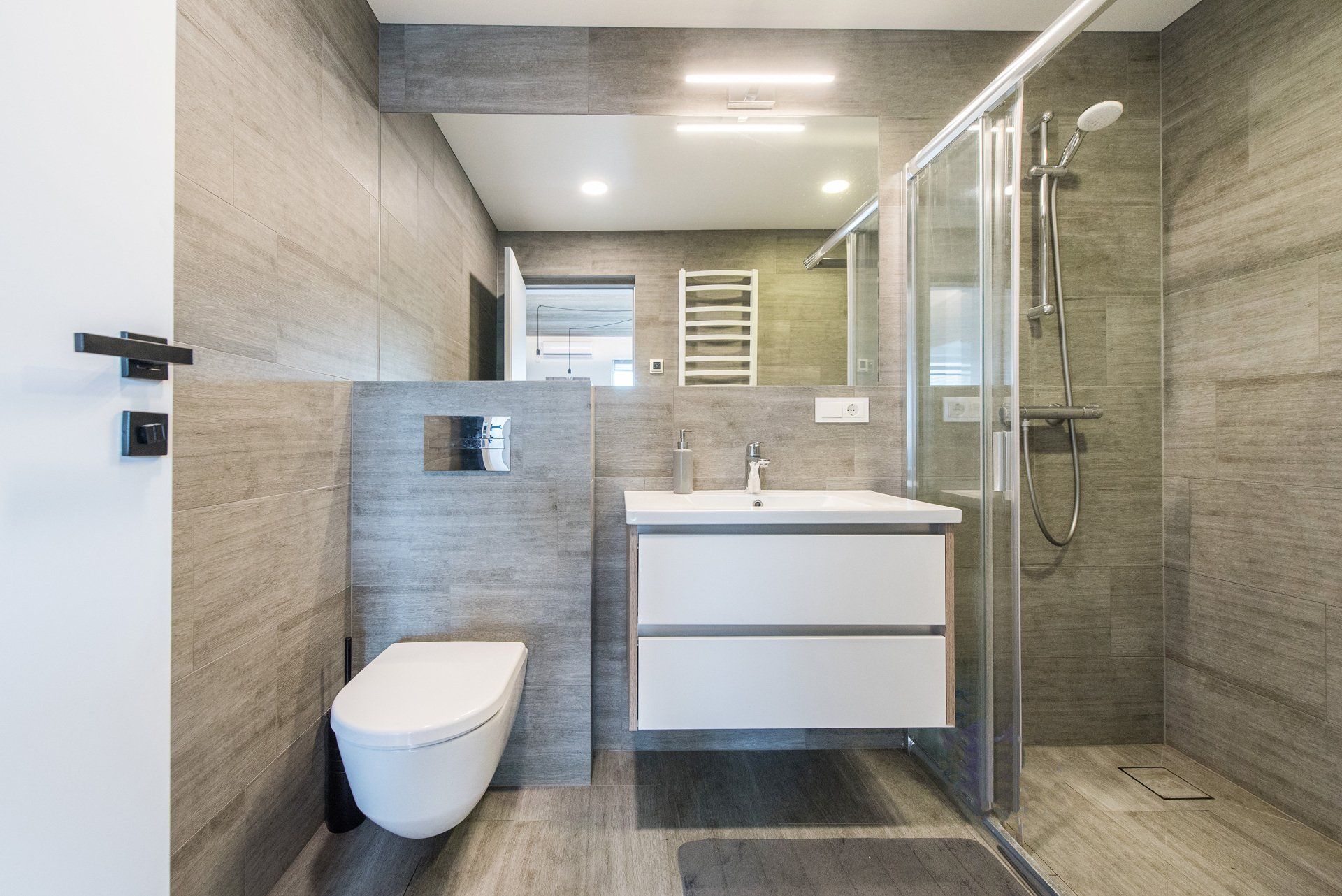 Vonios kambarys su tualetu, kriaukle ir dušo kabina.