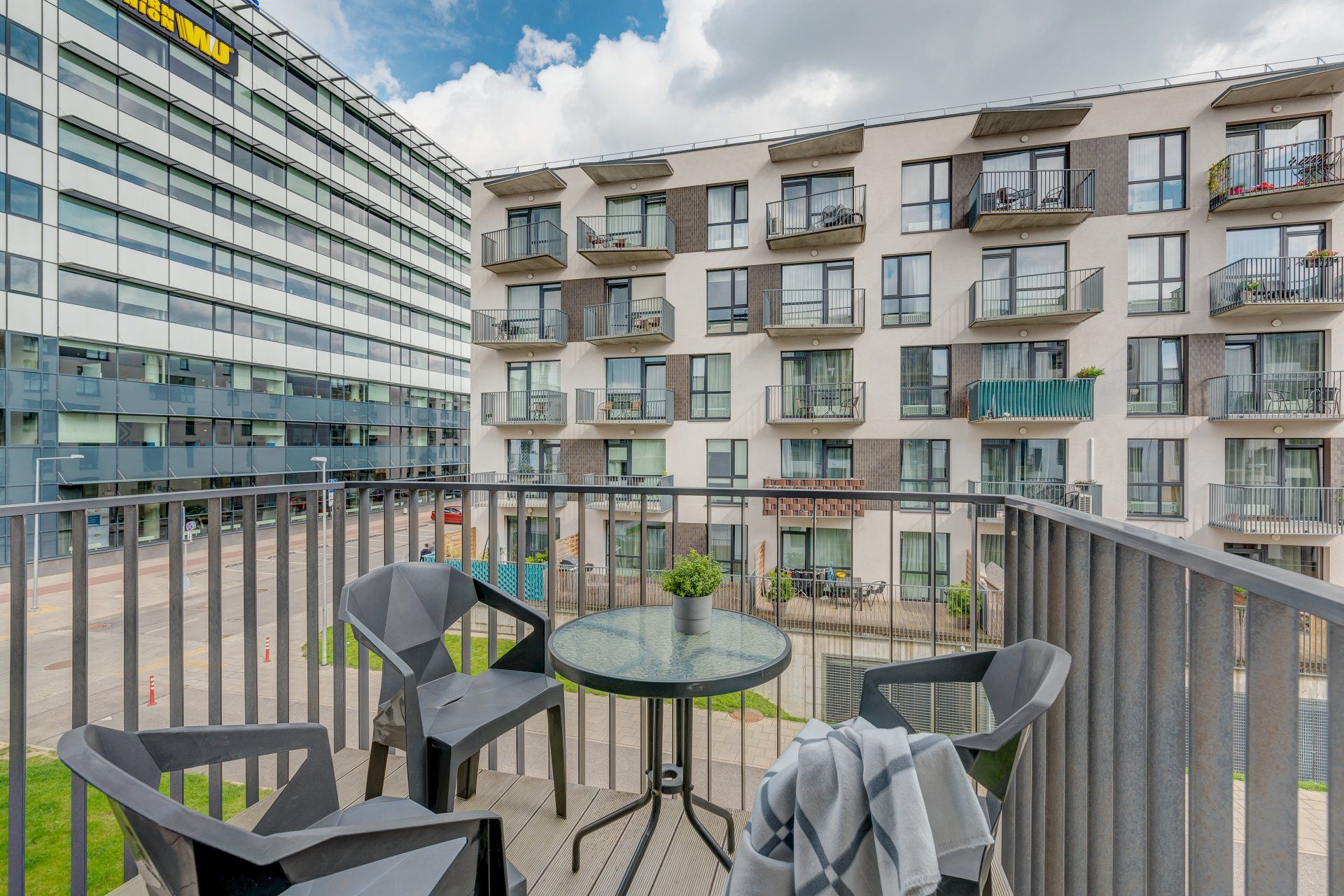 Balkonas su stalu ir kėdėmis priešais pastatą.