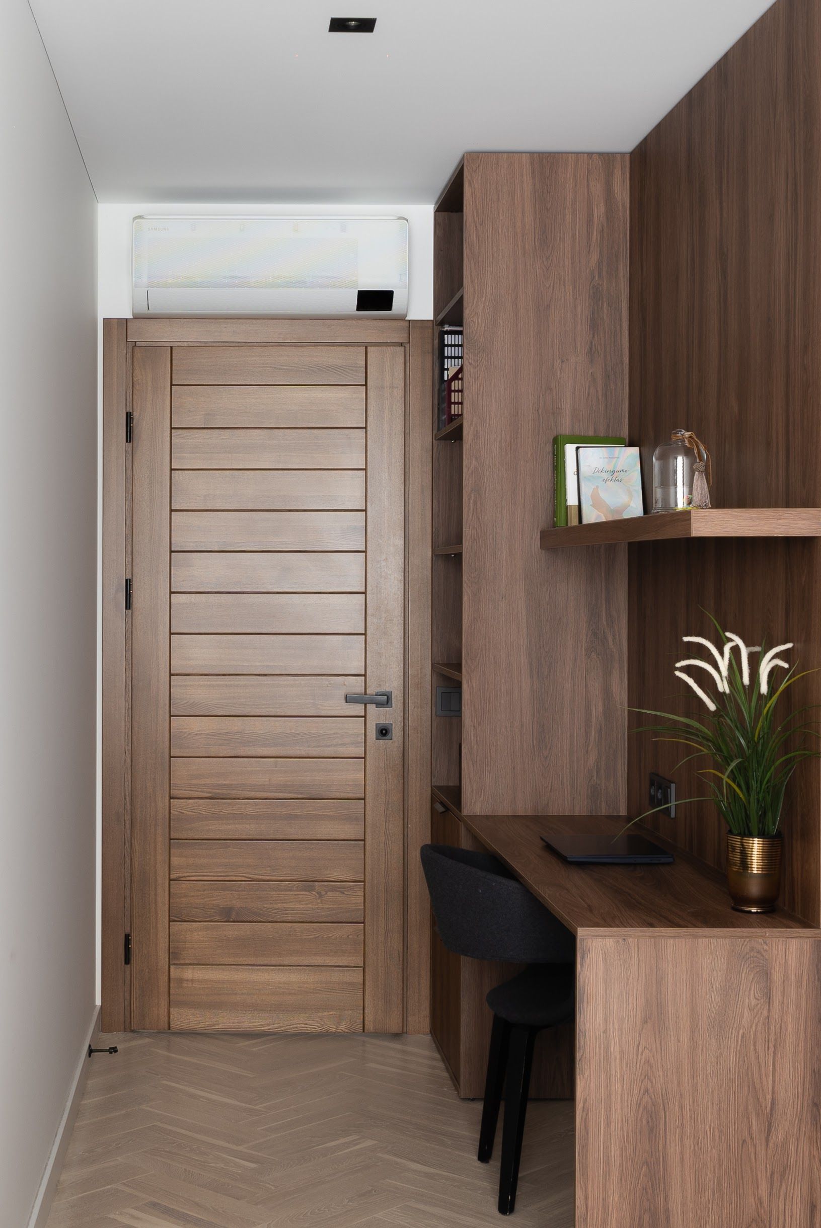 Koridorius su medinėmis durimis ir stalu su kėde.