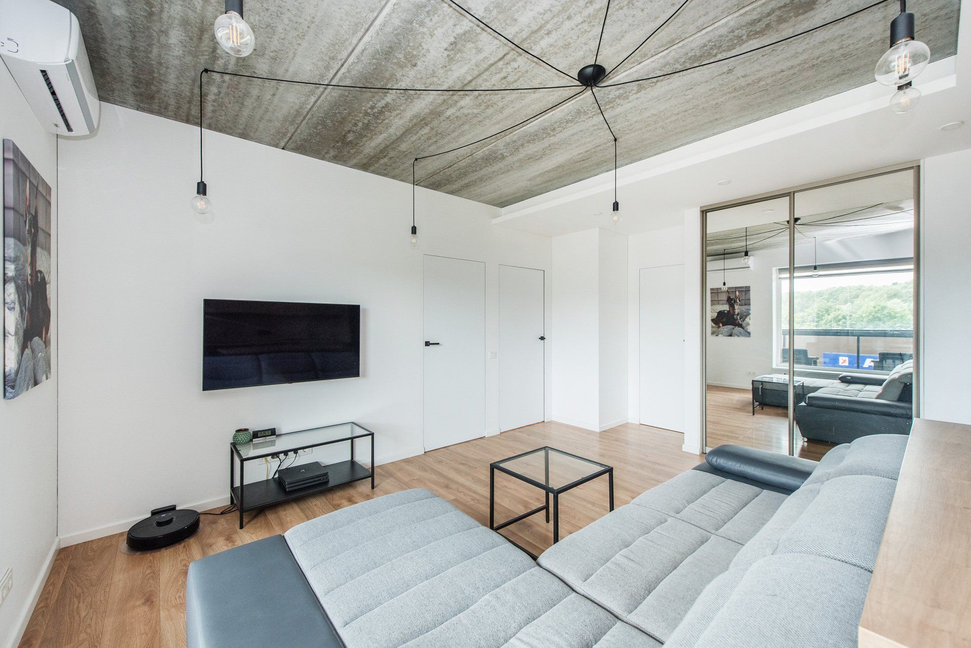 Svetainė su sofa ir plokščiaekraniu televizoriumi.