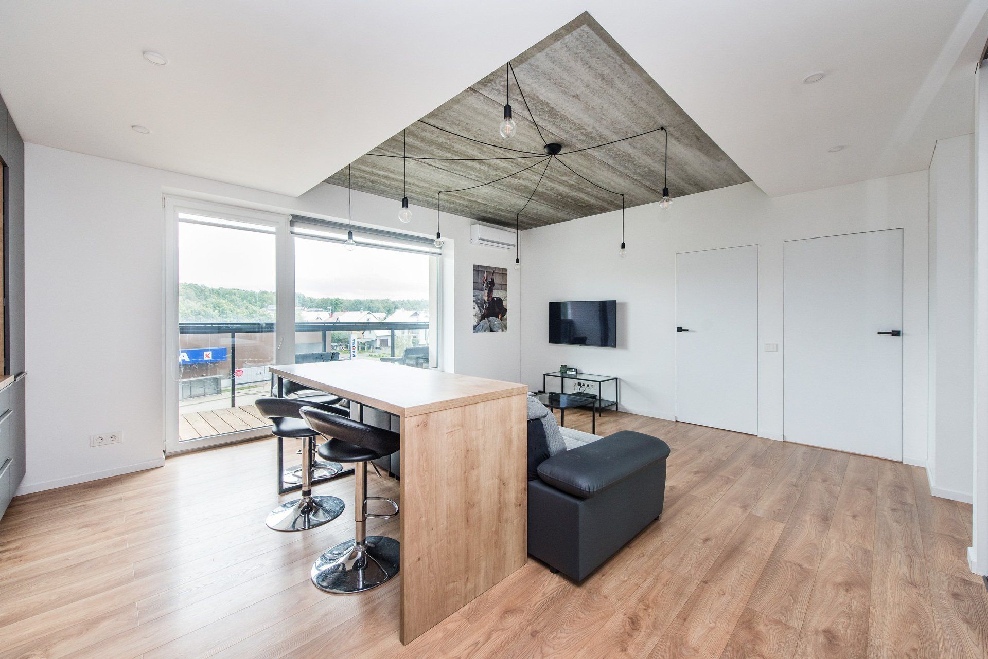 Svetainė su dideliu stalu ir plokščiaekraniu televizoriumi.