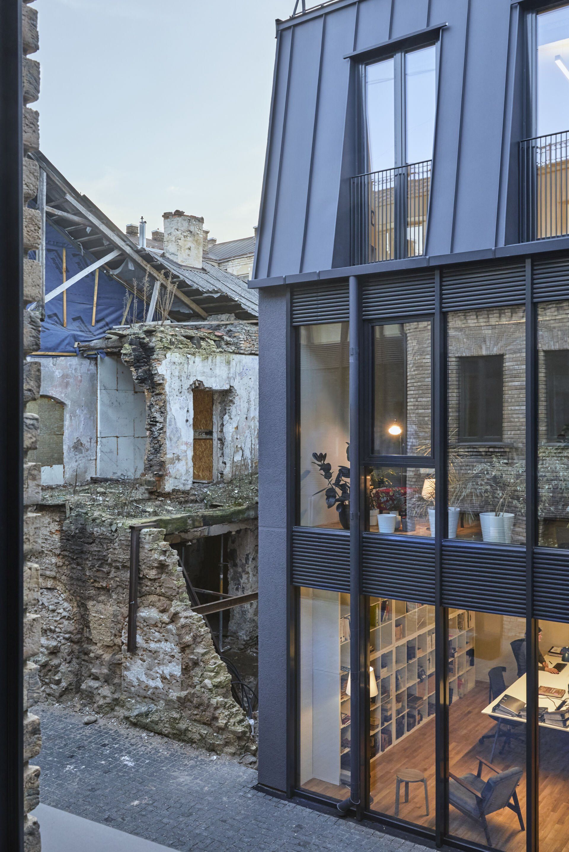 Didelis pastatas su daugybe langų ir plytų pastatu fone.