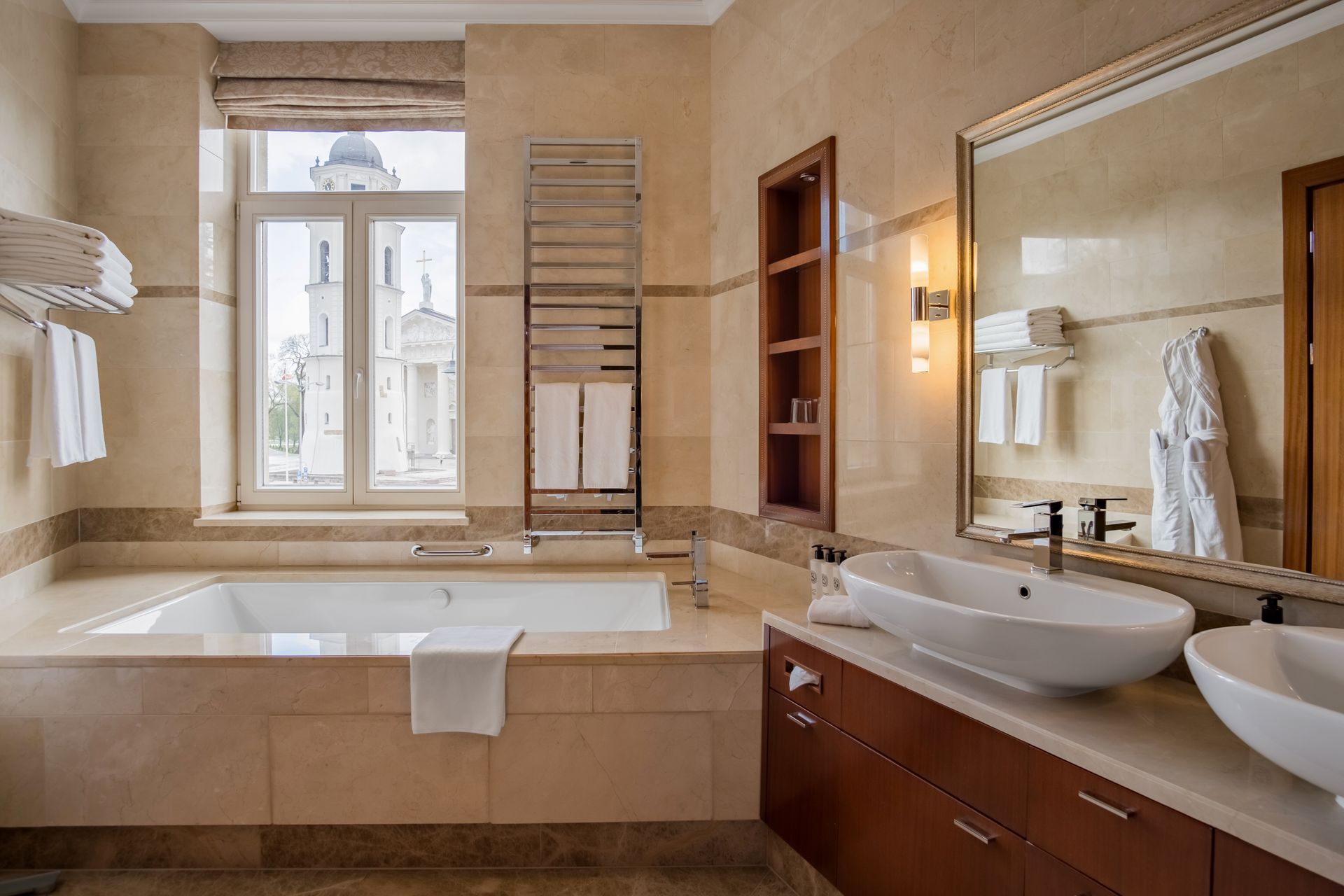 Vonios kambarys su vonia, kriaukle, veidrodžiu ir langu.