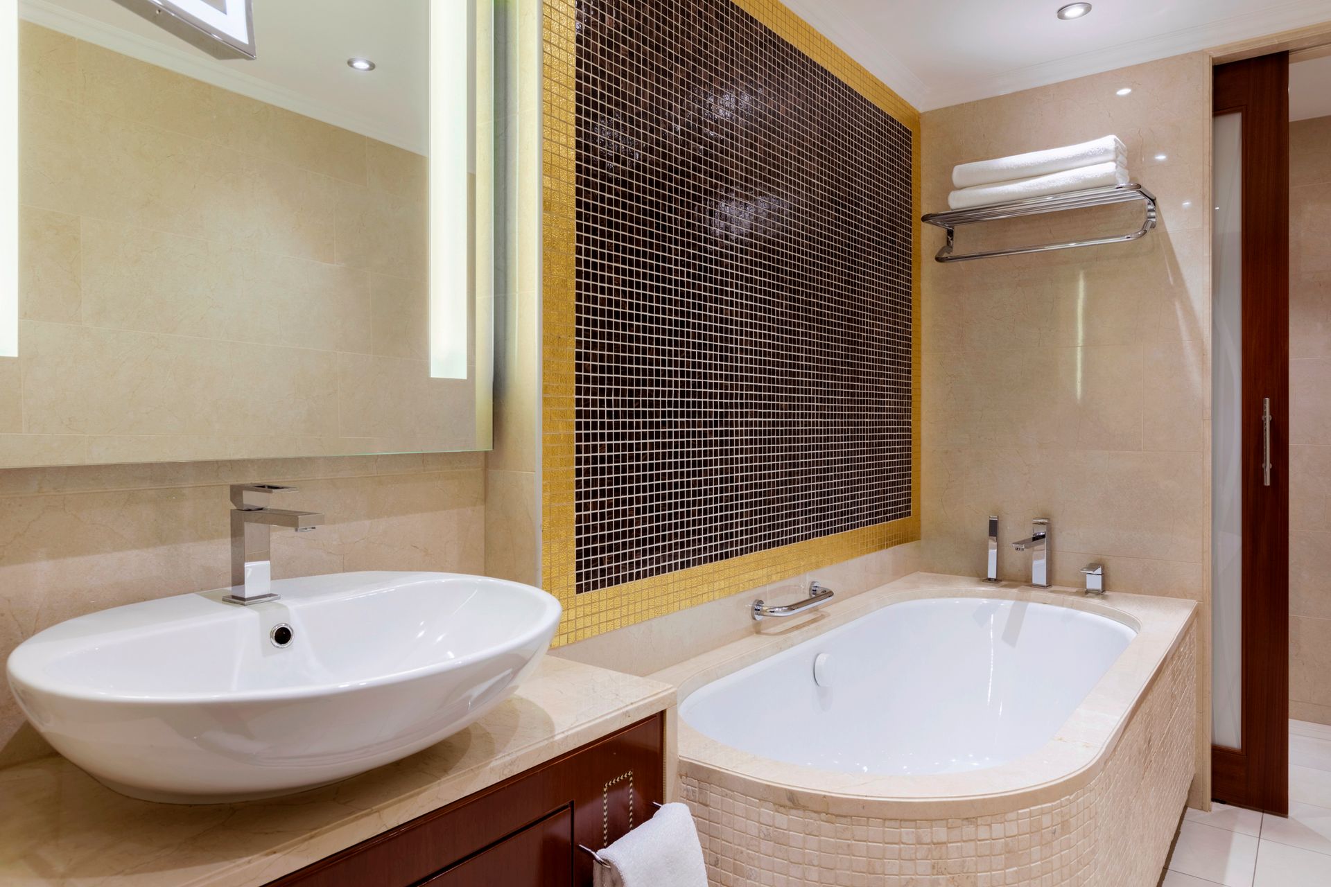 Vonios kambarys su vonia, kriaukle ir veidrodžiu.