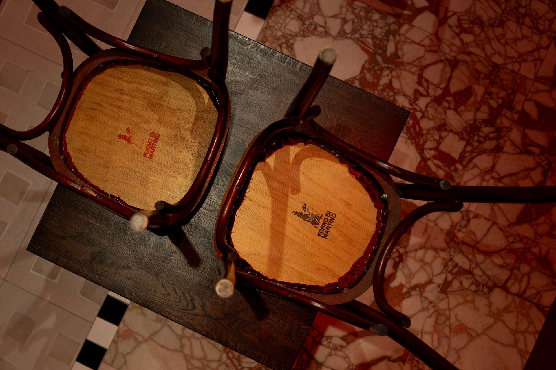 Two antique wooden chairs on patterned floor. View is from above, showing the seats.