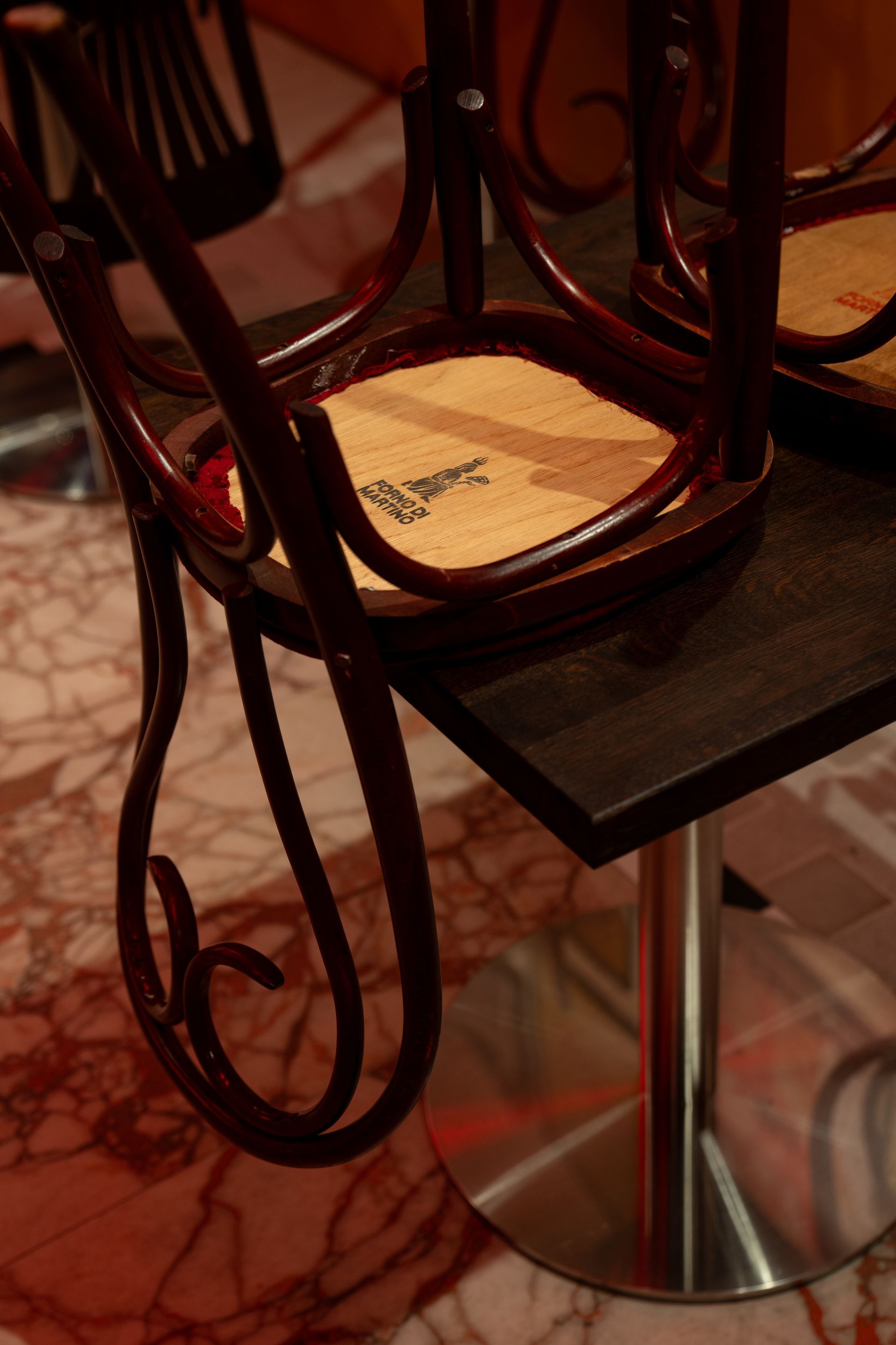 Wooden chair upside down on black table with marble floor.