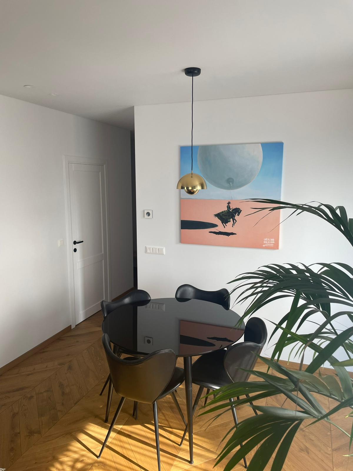 Valgomasis su stalu, kėdėmis ir paveikslu ant sienos.