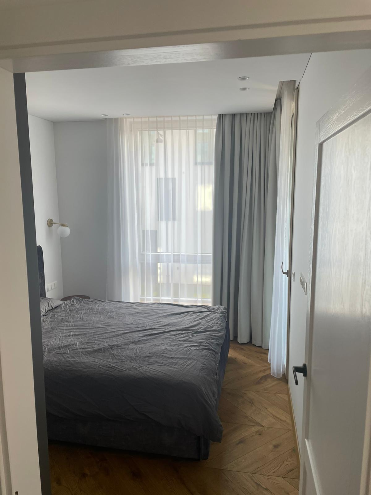 Miegamasis su lova, užuolaidomis ir langu.