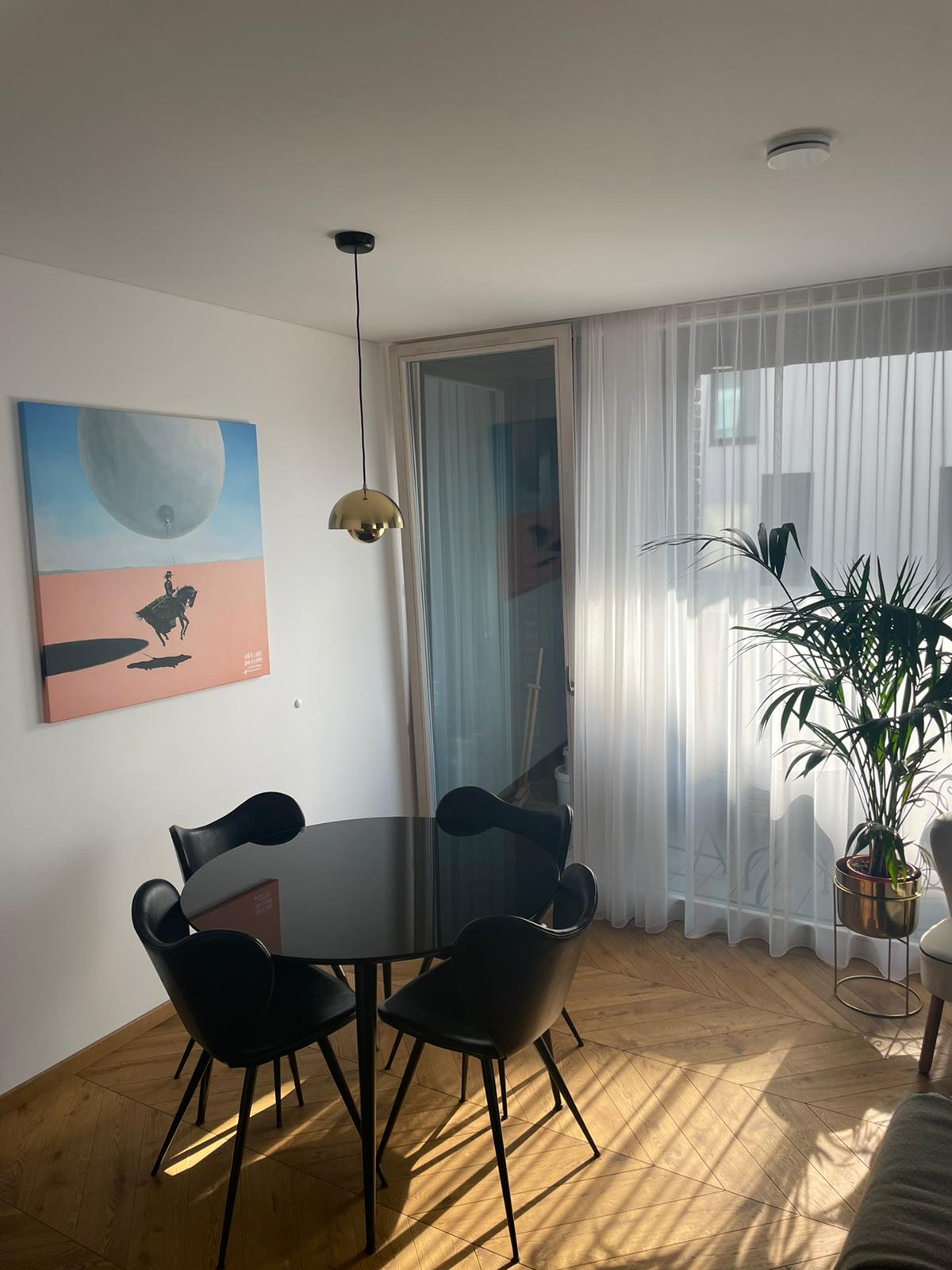 Valgomasis su stalu, kėdėmis ir paveikslu ant sienos.