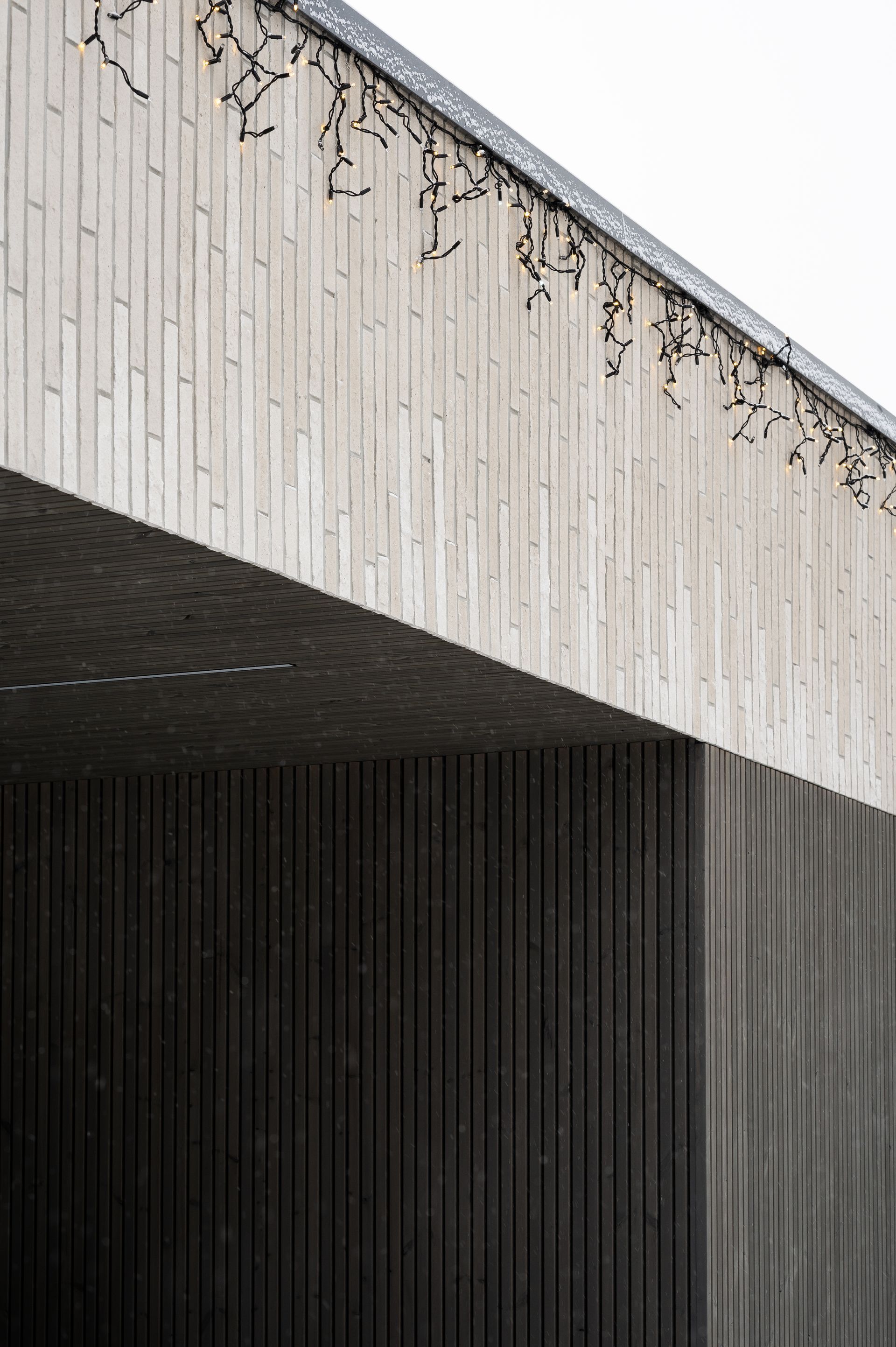 Concrete building exterior with textured surfaces, angled roof, and vertical lines.