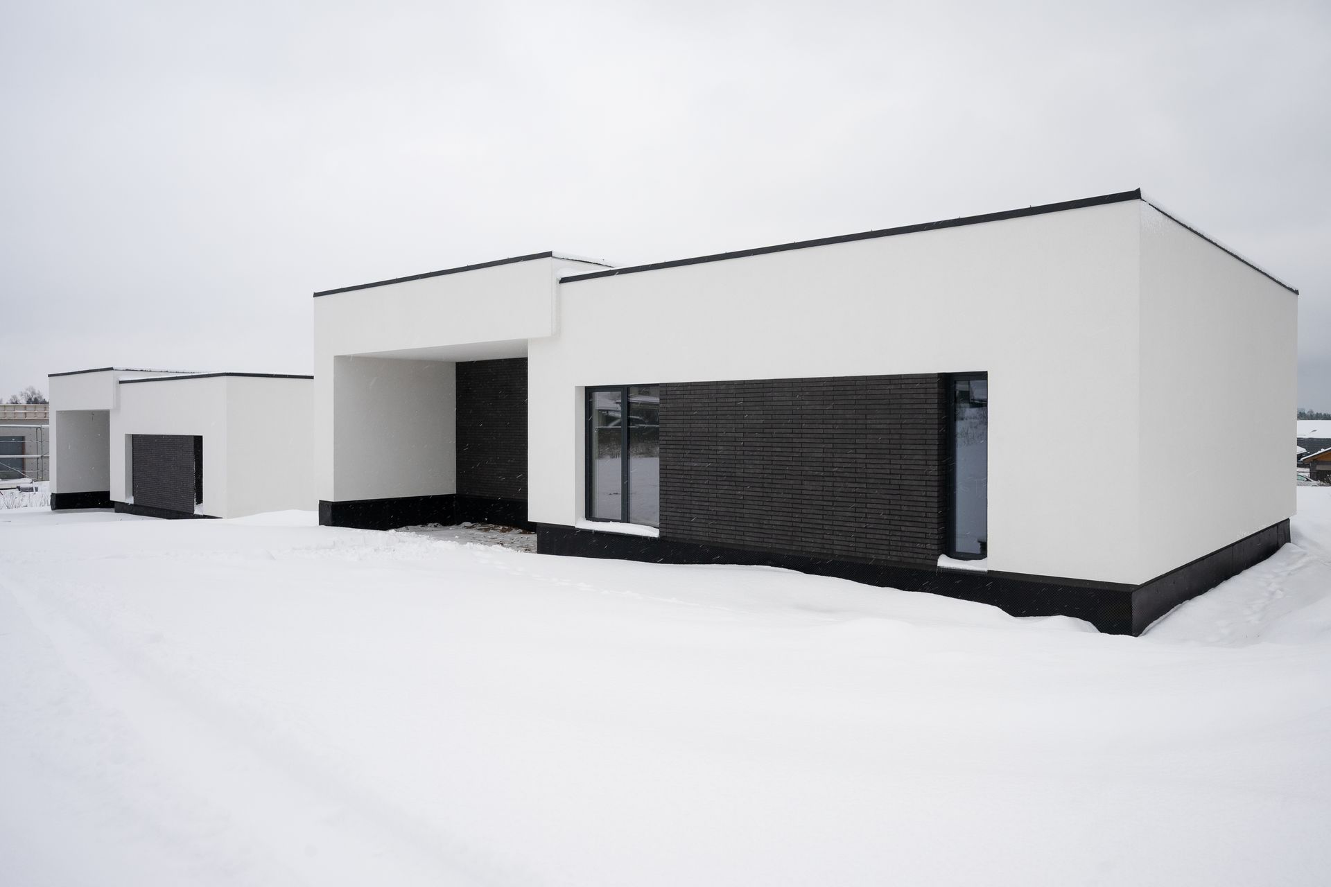 White modern buildings with dark trim against a snowy backdrop.