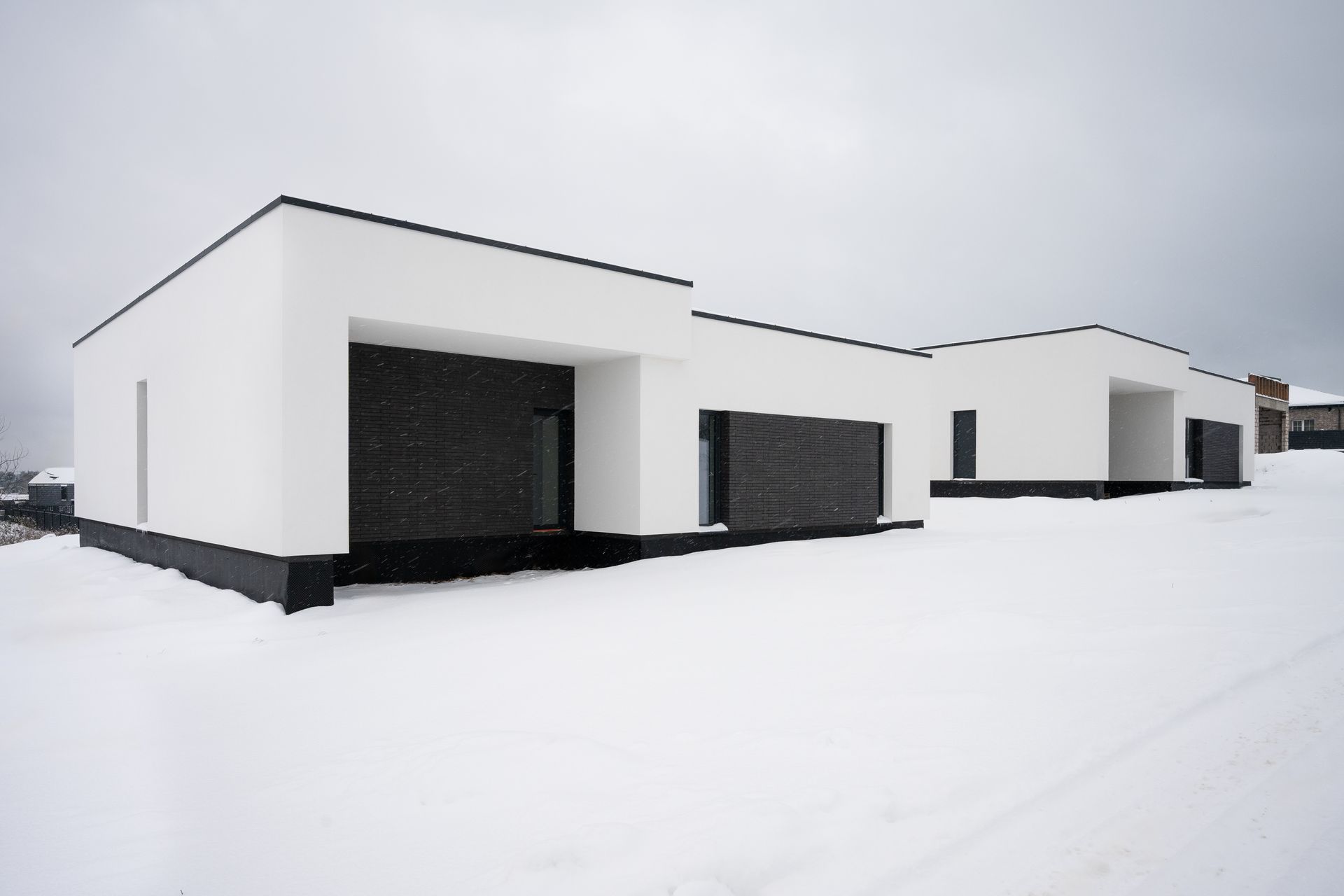 White and black modern houses in a snowy landscape.