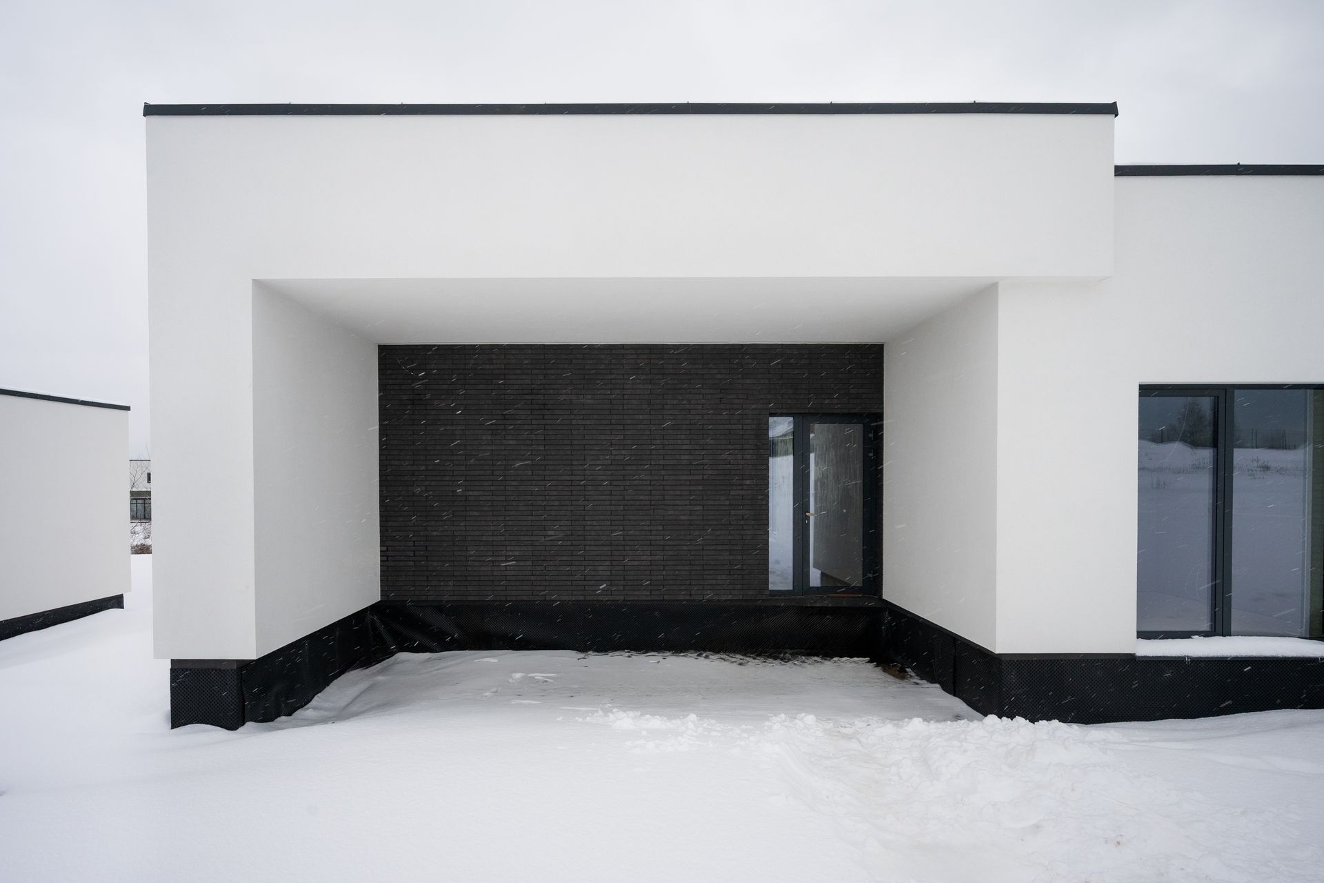White modern building with black accent wall, snowy ground.