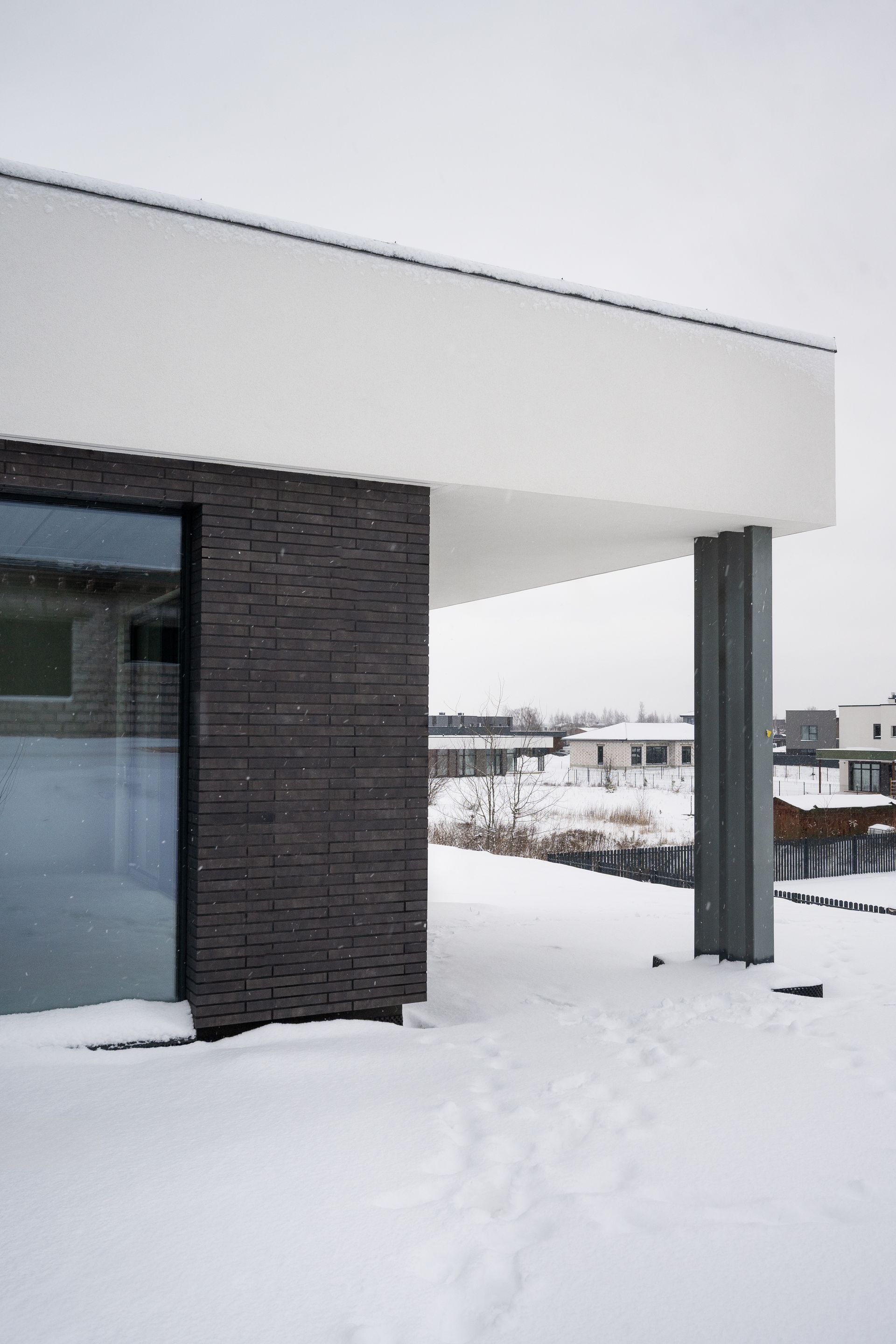 Modern building exterior with snowy ground, brick wall, and large window.