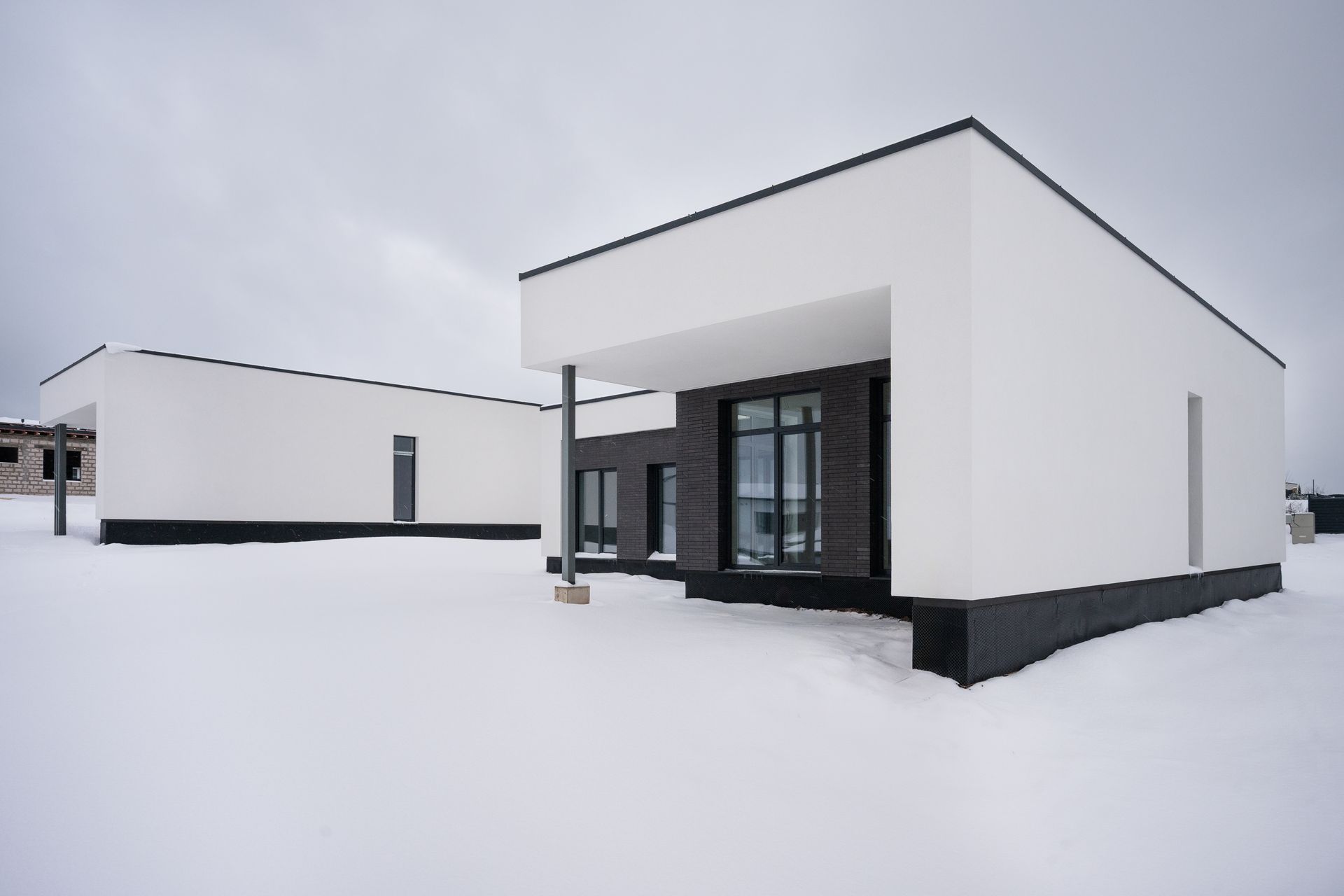 Modern white houses with black accents stand in a snowy landscape.
