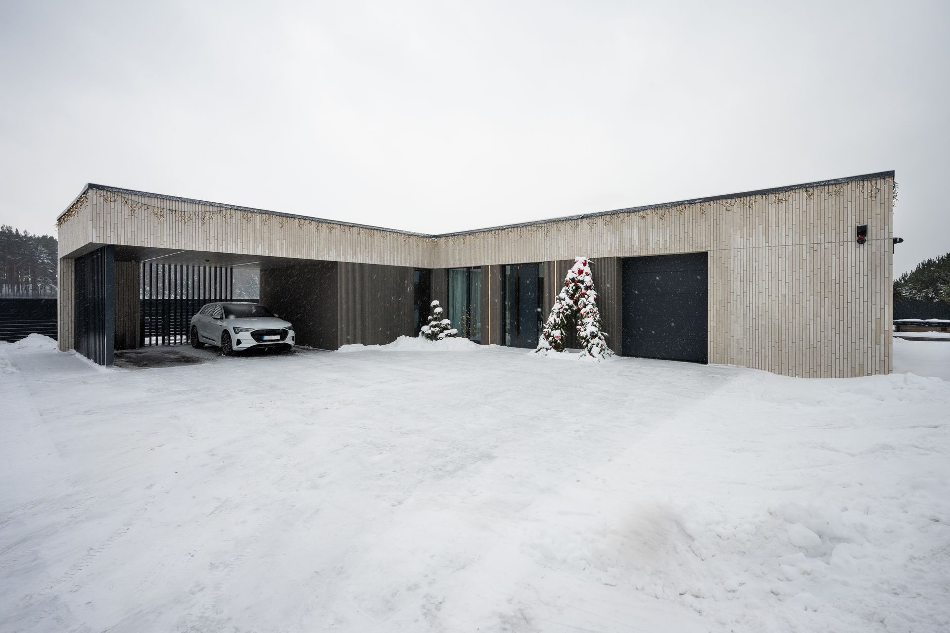 Exterior view of a modern concrete building in a snowy setting, with a car parked inside.