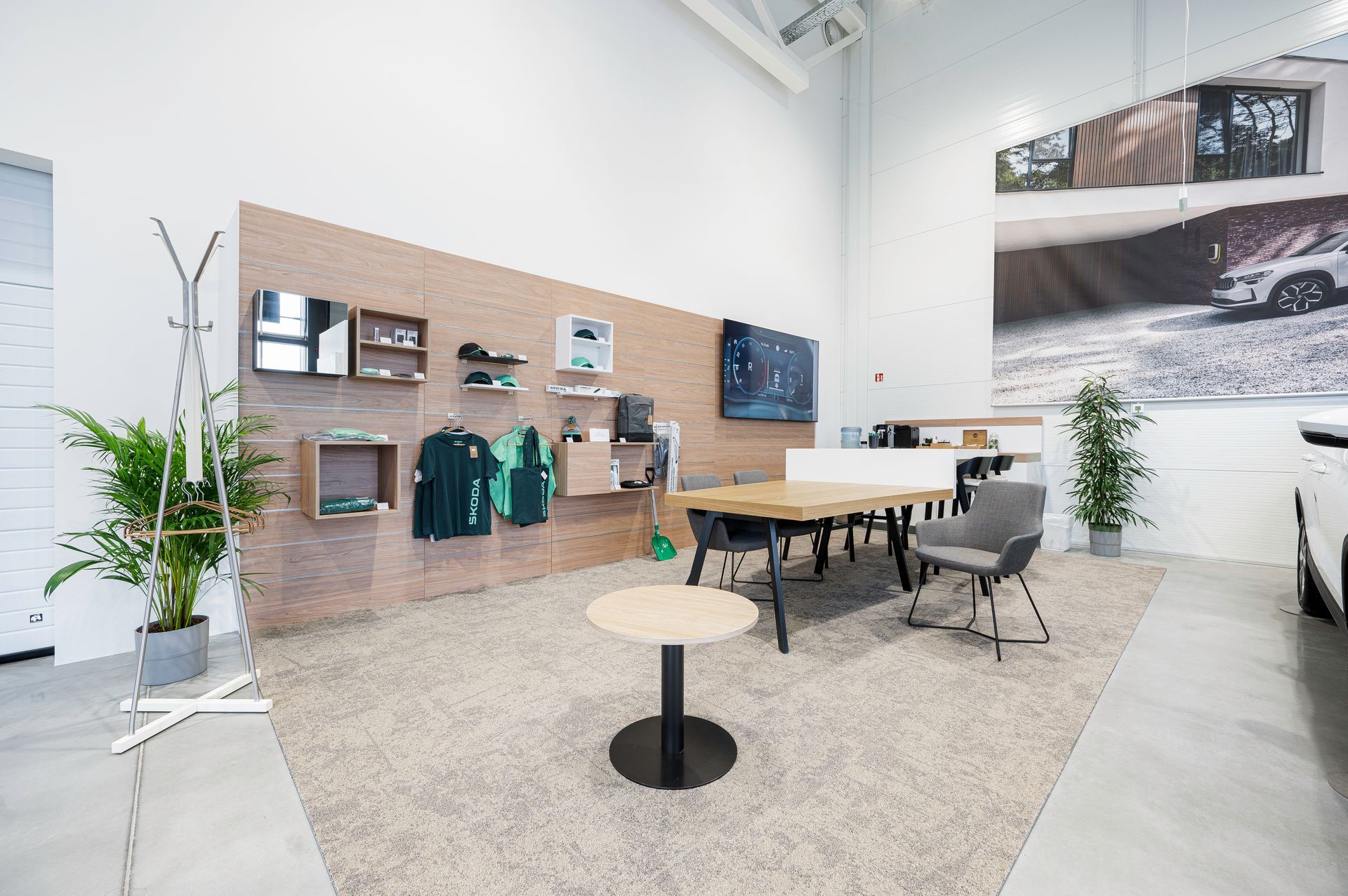 Kambarys su stalu ir kėdėmis, o ant sienos kabo automobilio nuotrauka.