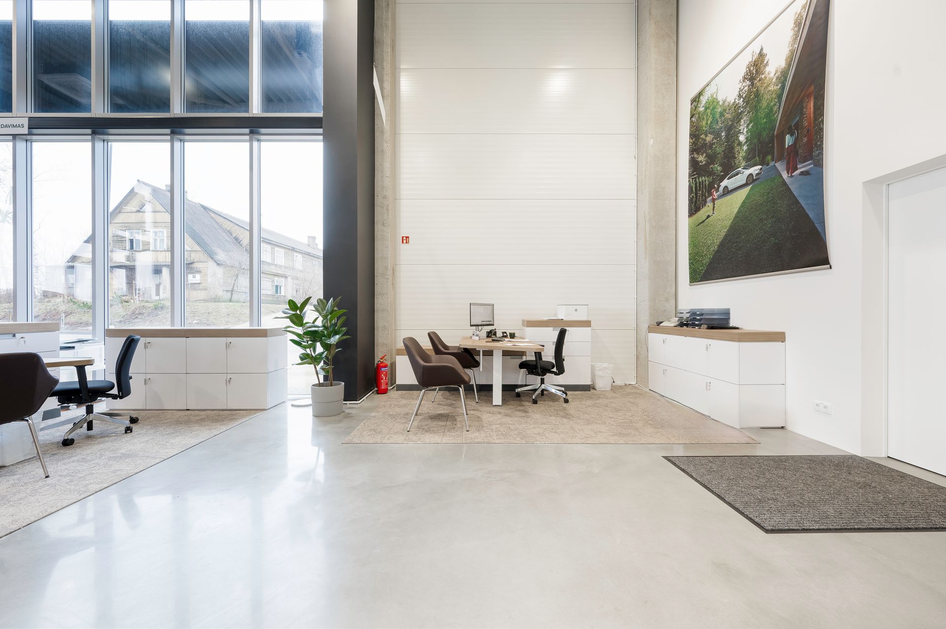 Didelis kambarys su daugybe langų ir paveikslu ant sienos.