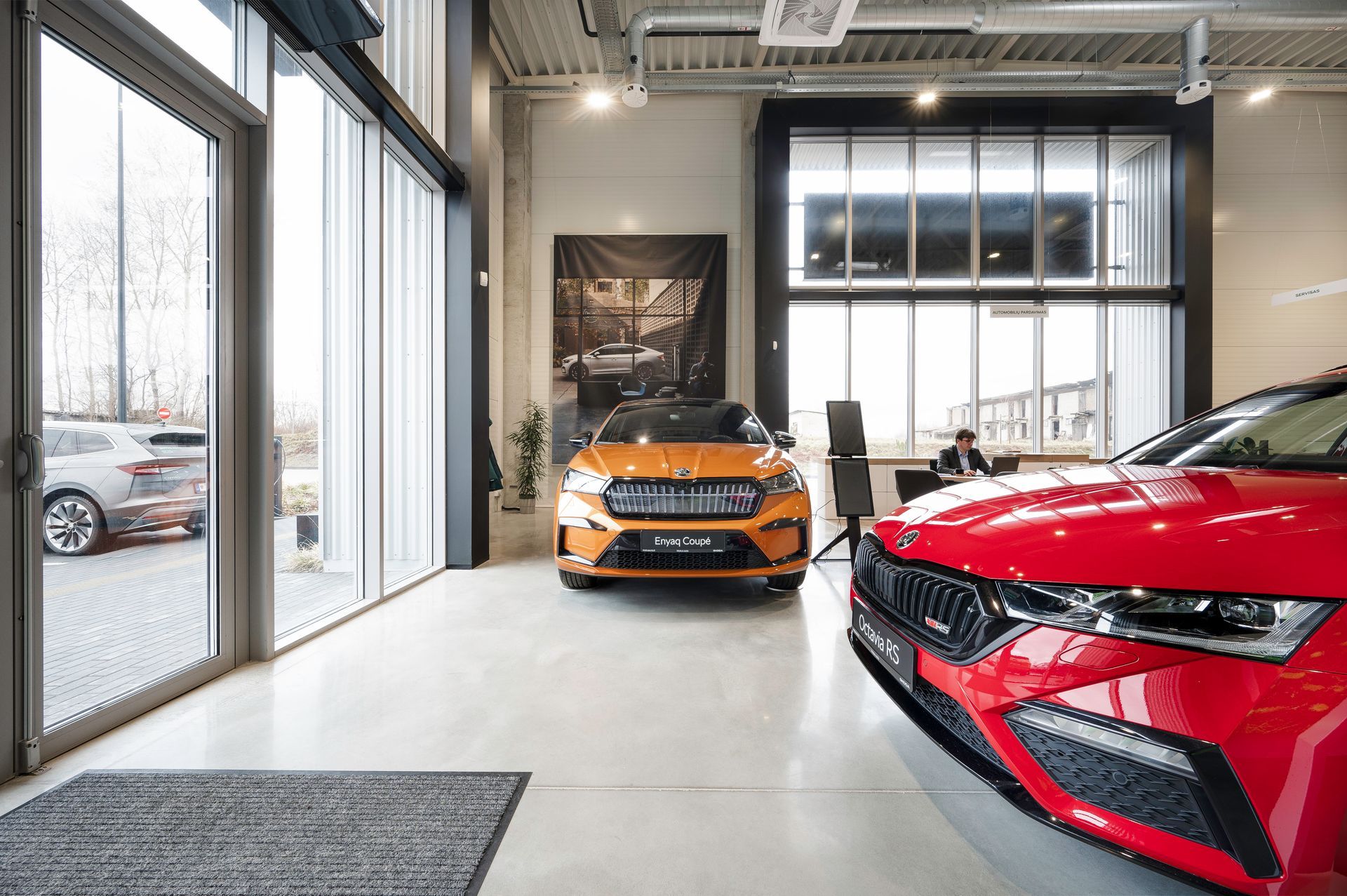 Du automobiliai stovi salone vienas šalia kito.