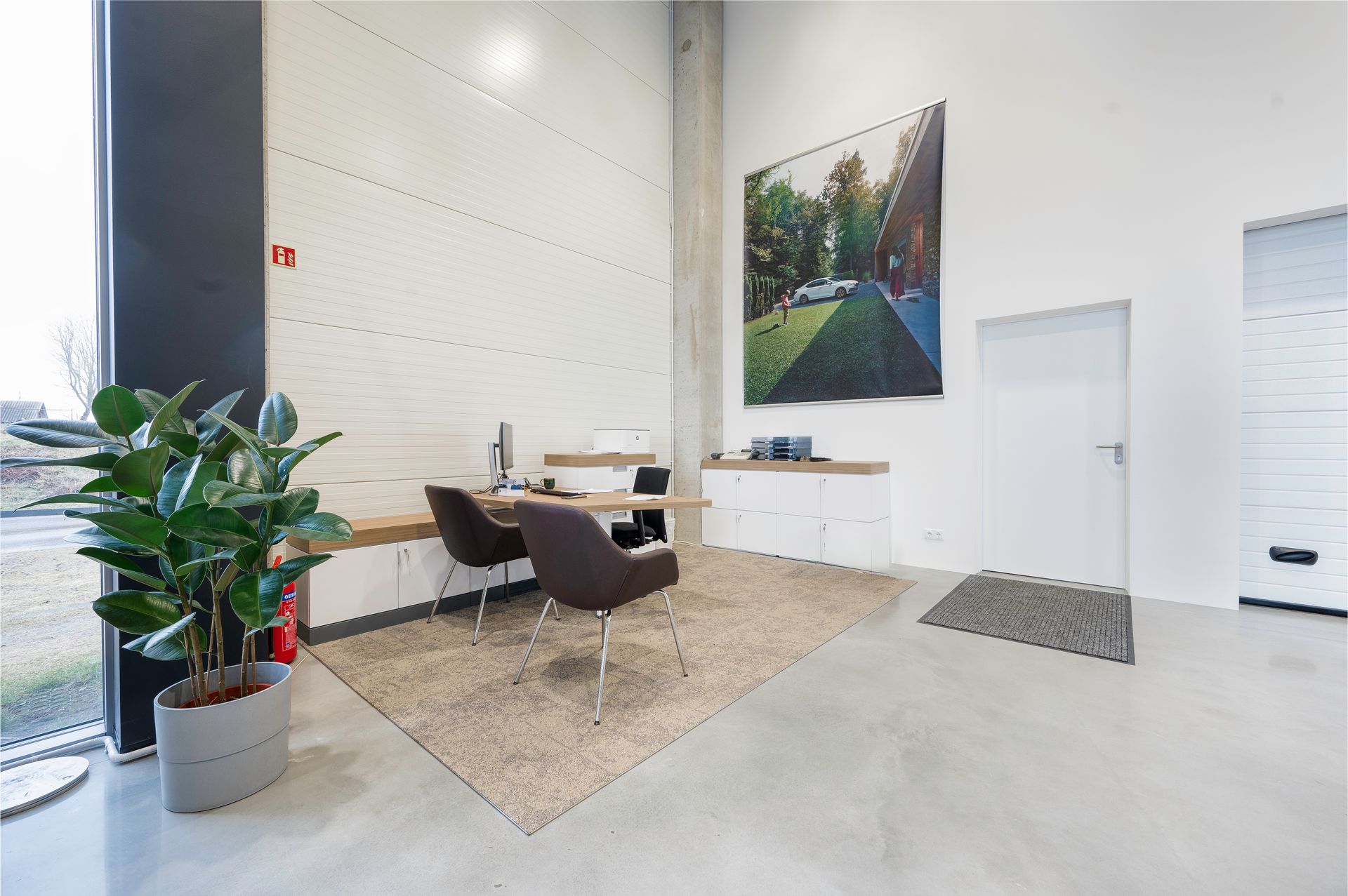 Kambarys su dviem kėdėmis, stalu, augalu ir paveikslu ant sienos.