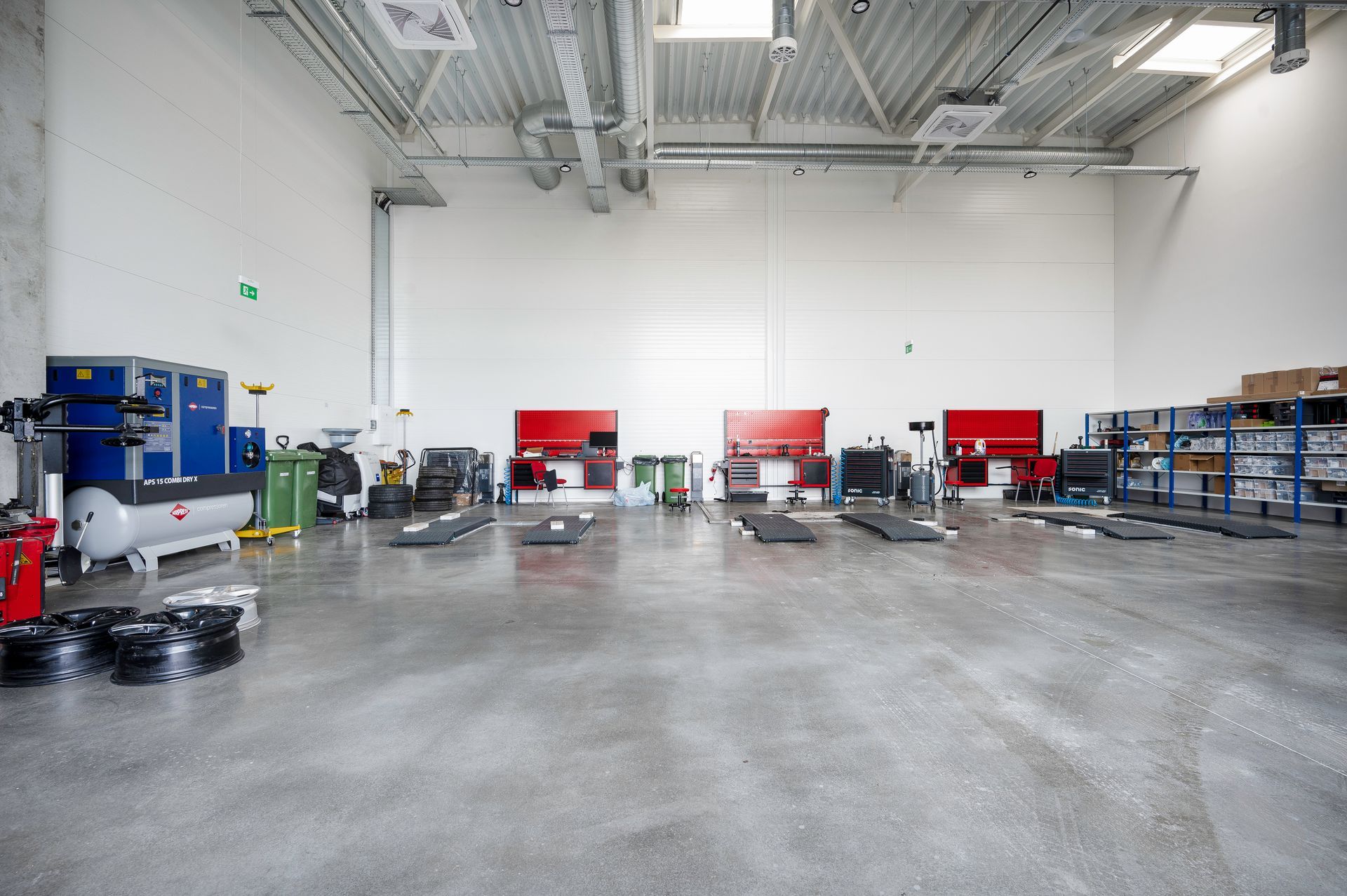 Didelis tuščias garažas su daugybe įrankių ir įrangos.