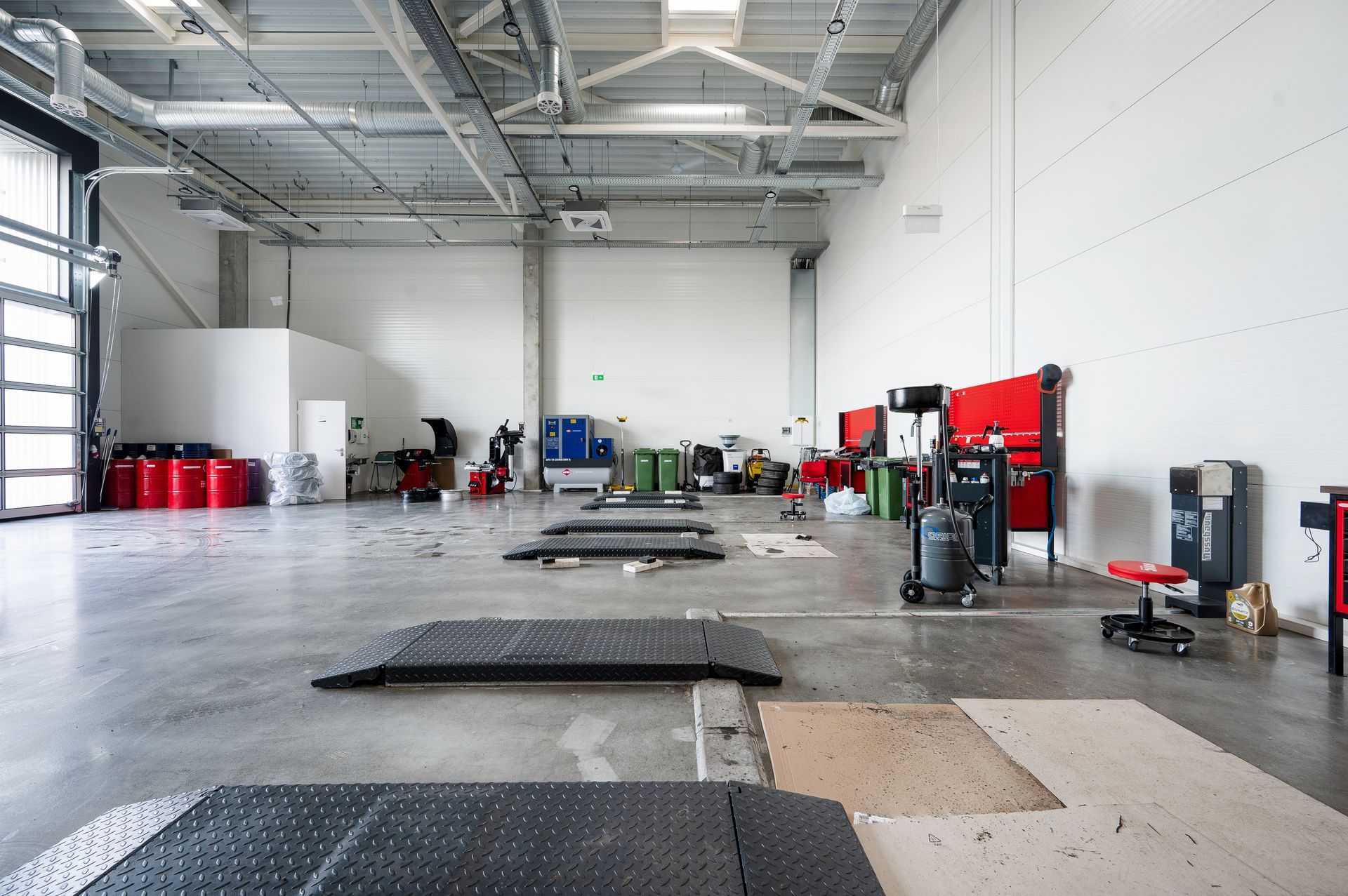 Didelis tuščias garažas su daugybe įrankių ir įrangos.