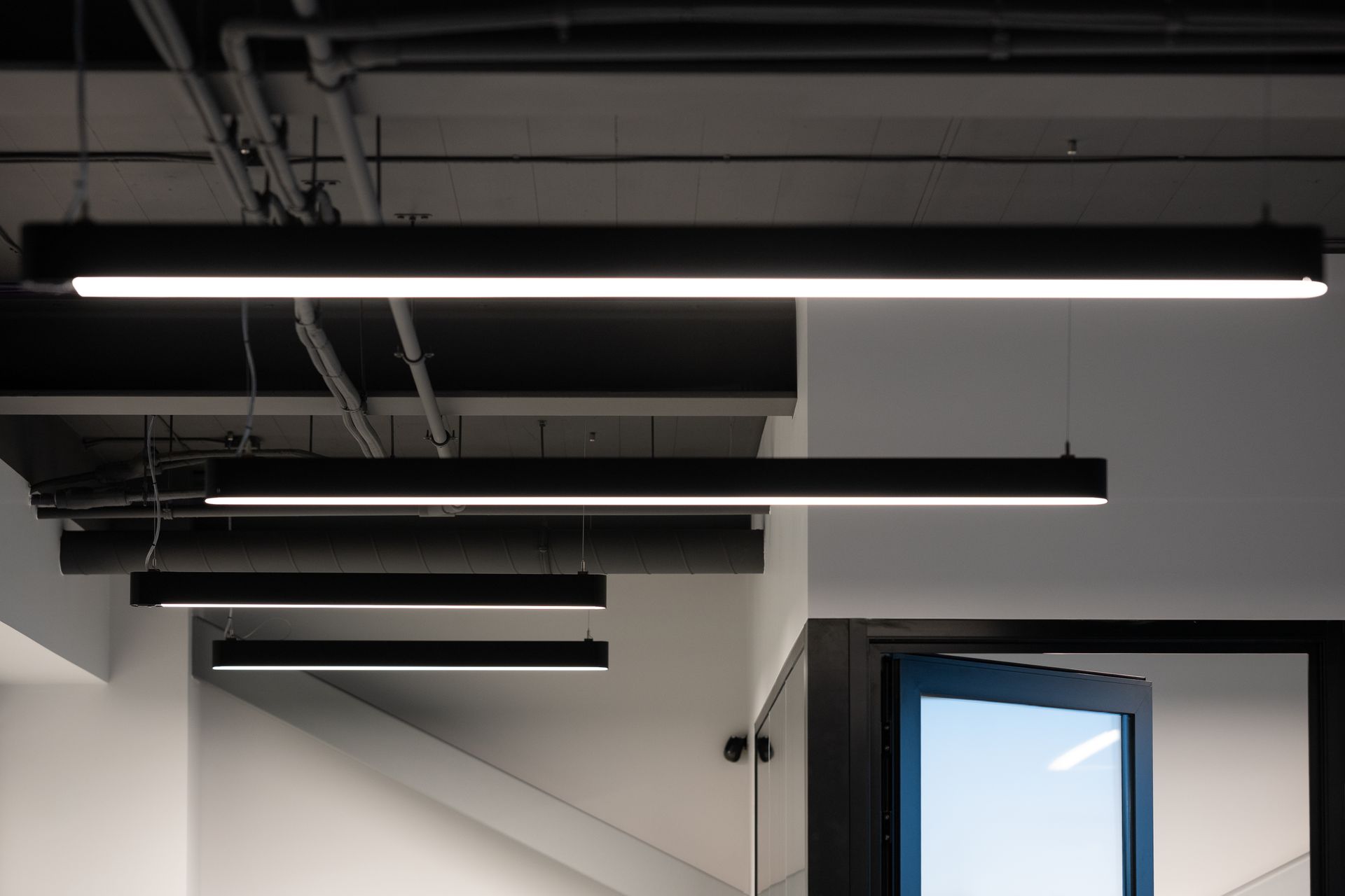 Black rectangular overhead lights in a modern office space.
