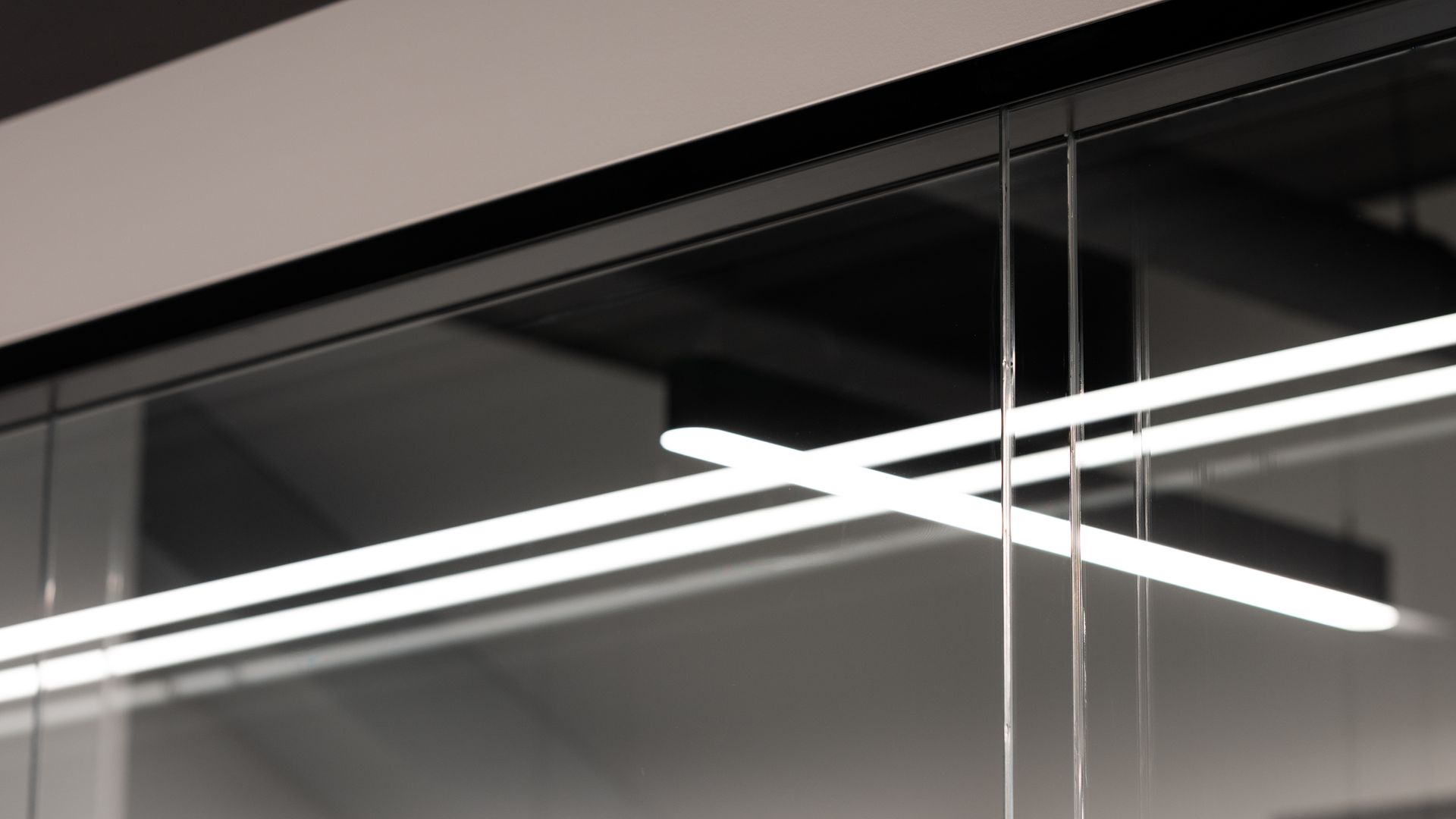Glass wall with linear LED lights and black ceiling details.
