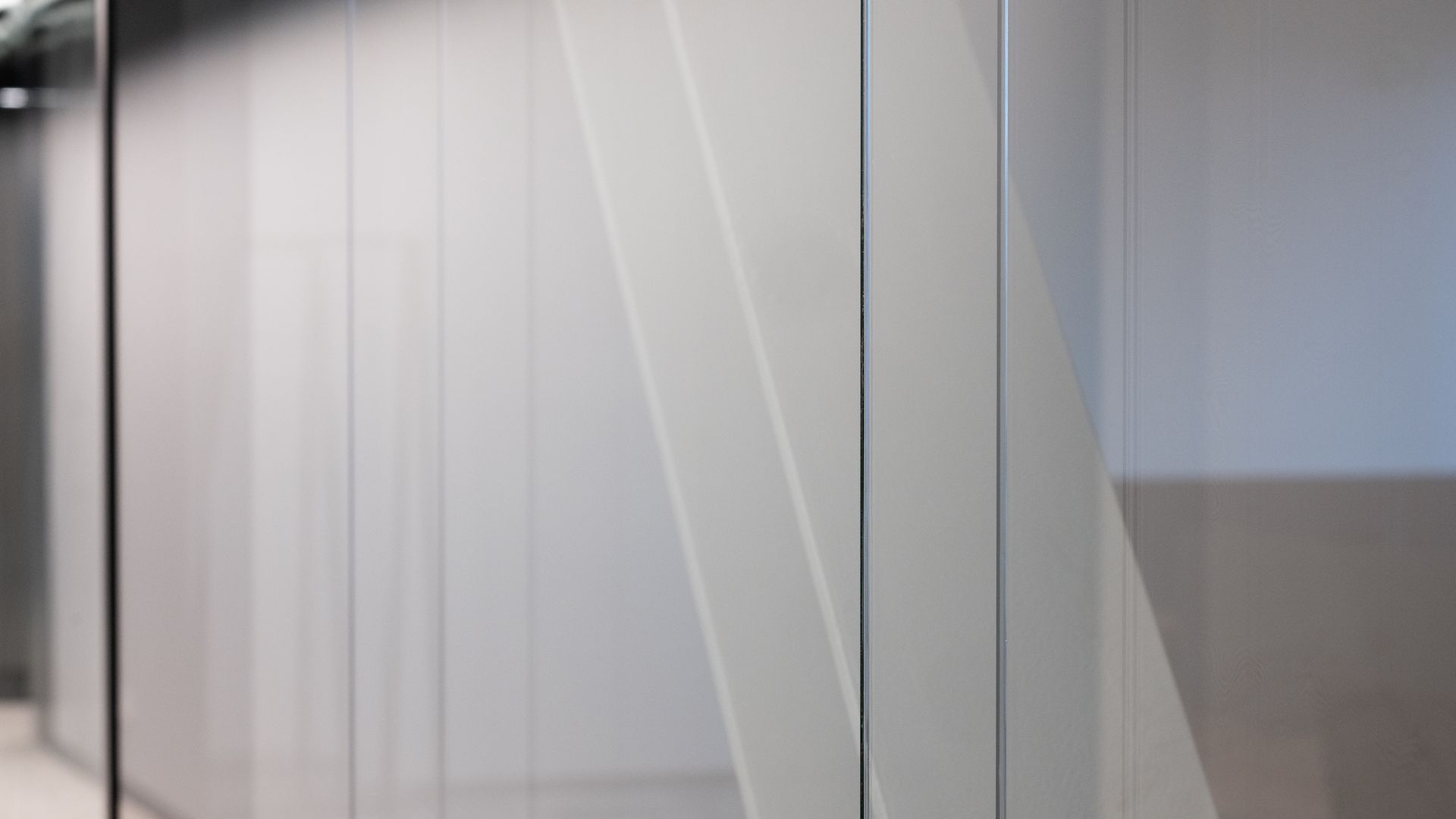 Glass office partition with white walls and a sheer fabric panel.