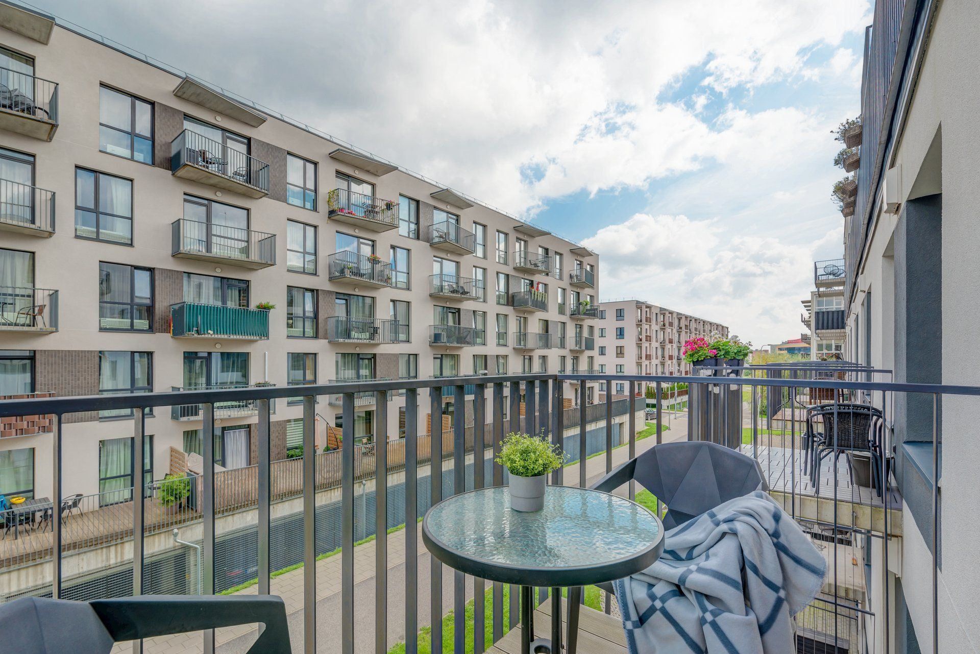 Balkonas su stalu ir kėdėmis priešais pastatą.