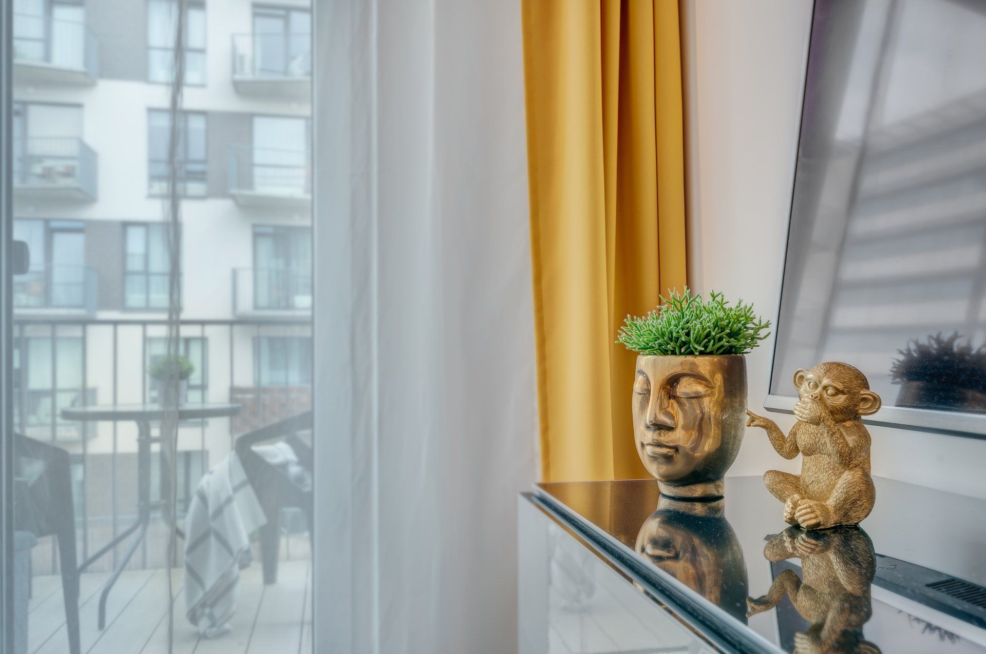 Ant stalo yra beždžionės statula ir vazoninis augalas.