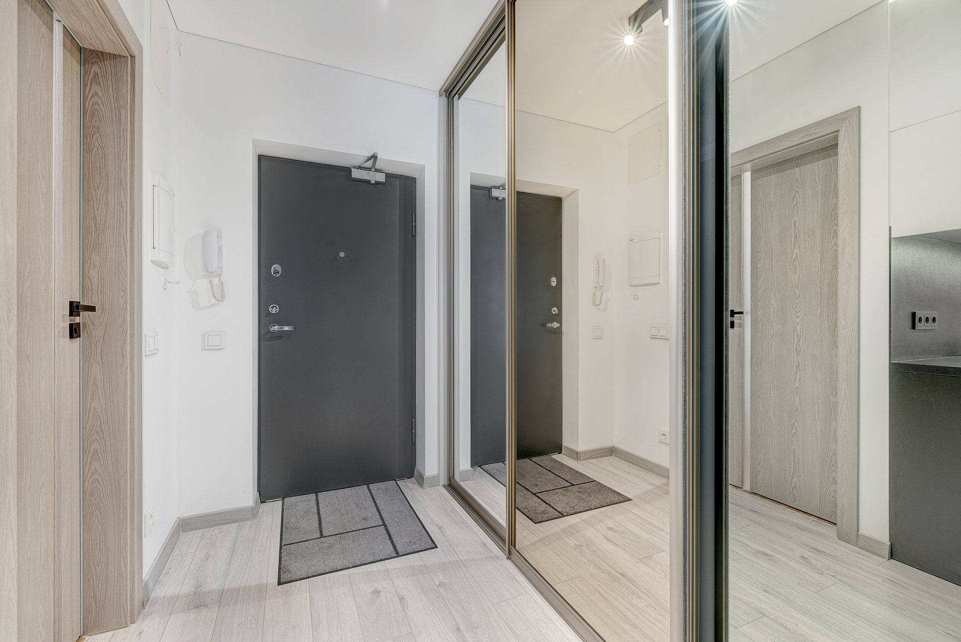 Koridorius su dideliu veidrodžiu tarp dviejų durų.