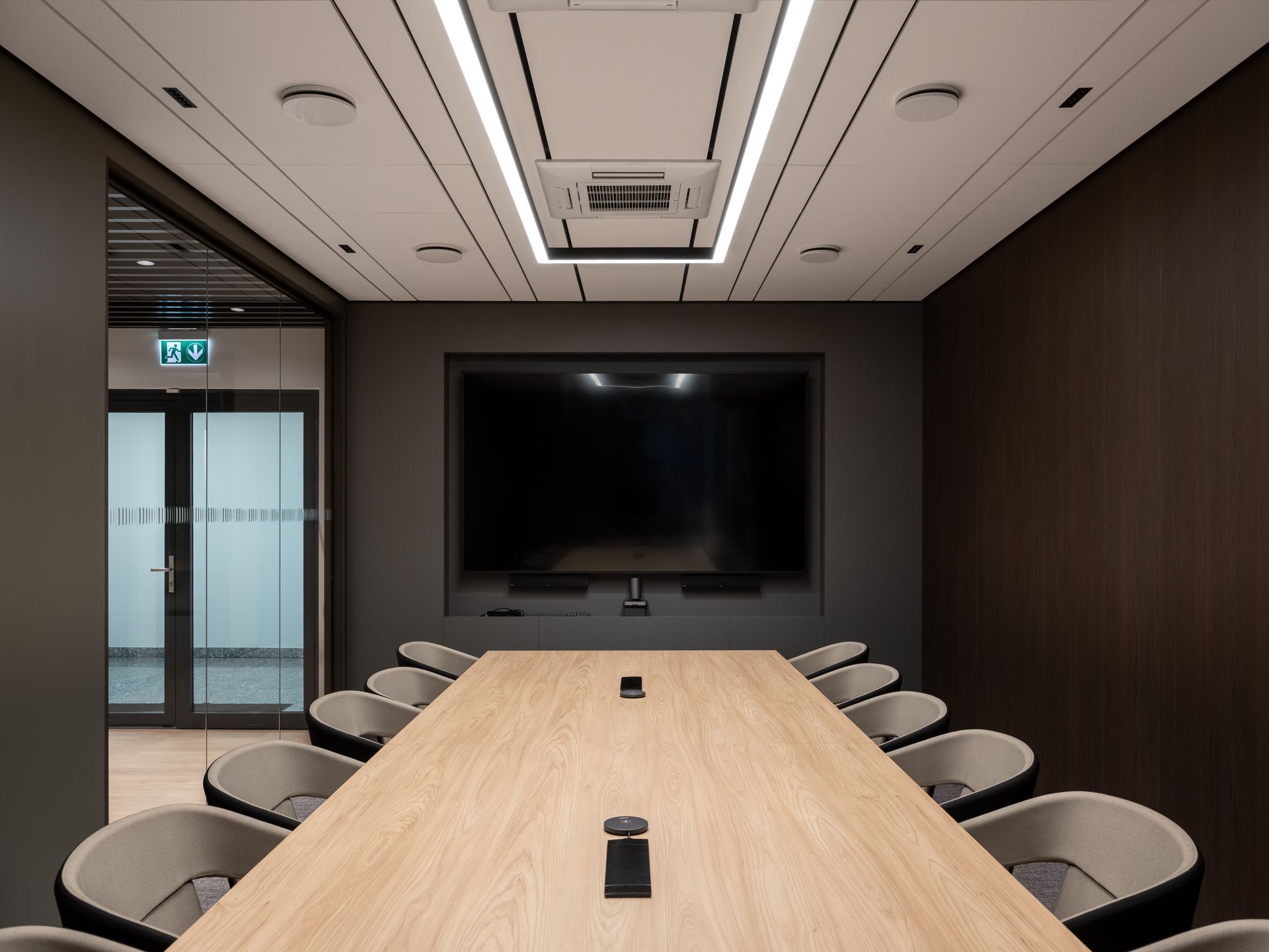 Konferencijų salė su ilgu mediniu stalu ir kėdėmis