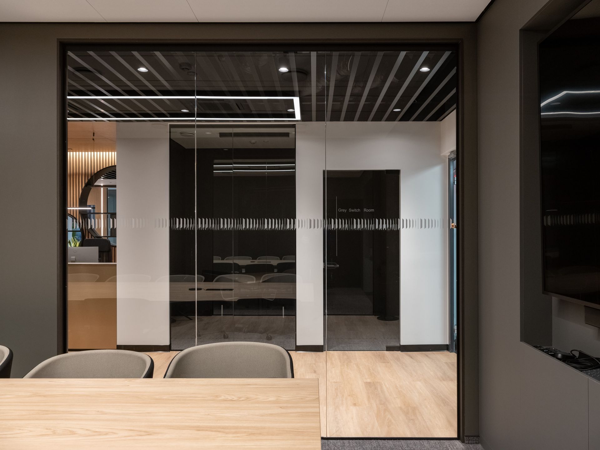 Konferencijų salė su stumdomomis stiklinėmis durimis ir mediniu stalu bei kėdėmis.