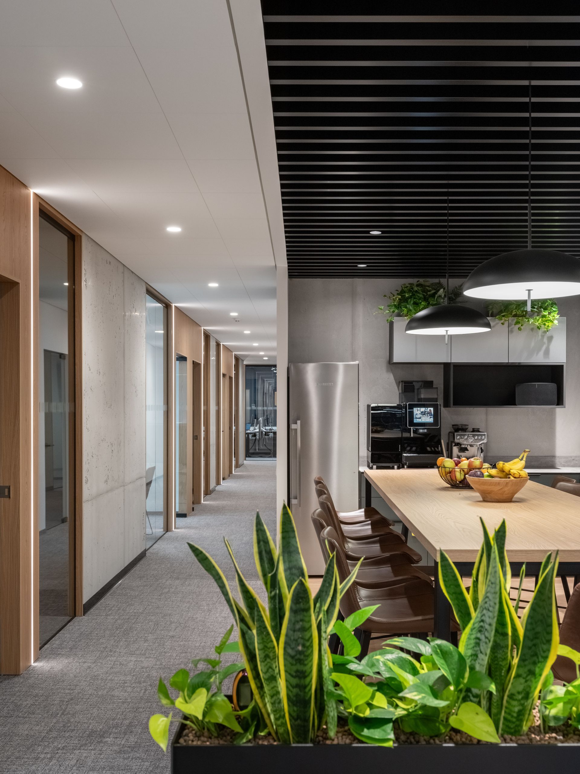 Ilgas koridorius, vedantis į virtuvę su stalu ir kėdėmis.