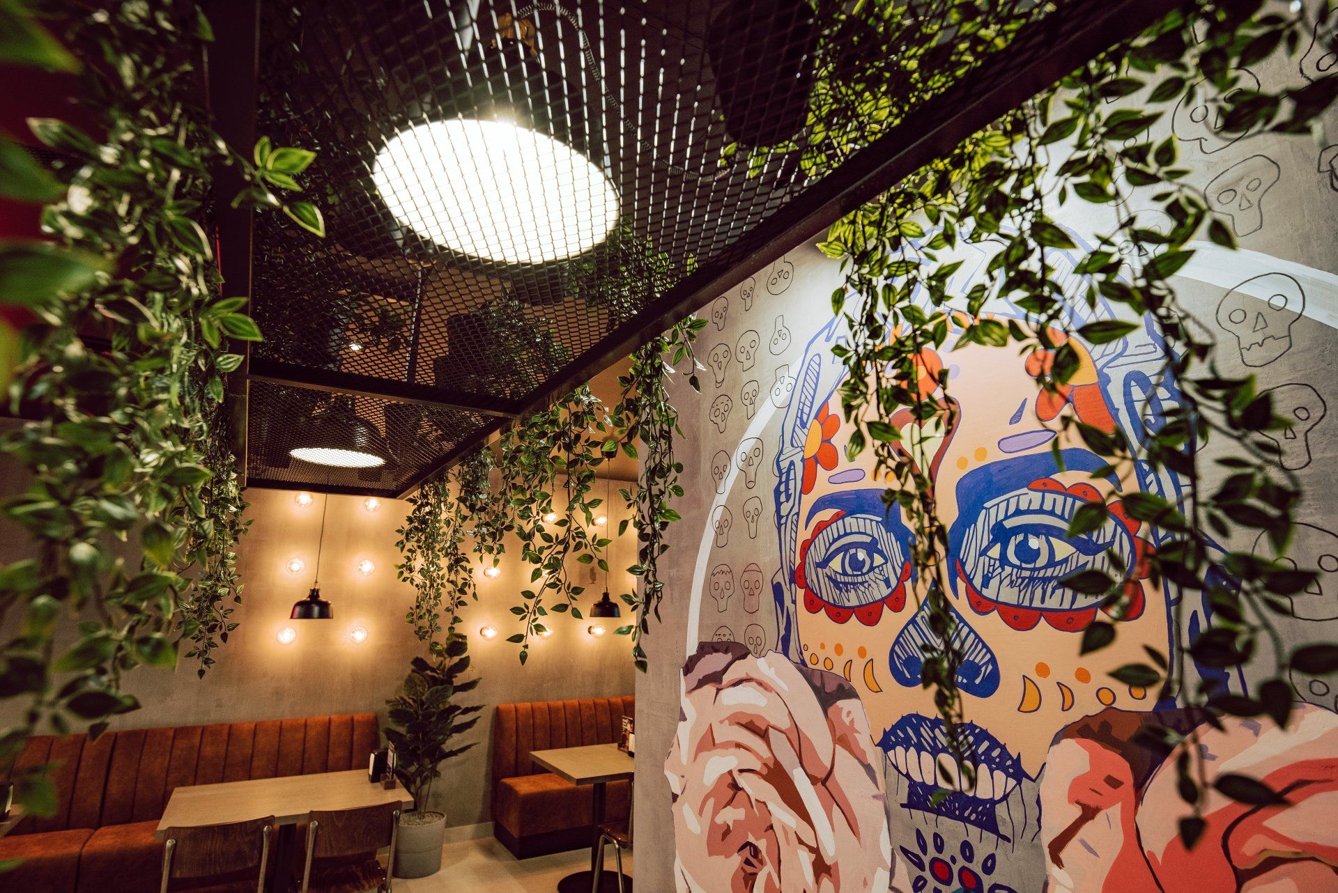 Kambarys su stalais, kėdėmis ir paveikslu ant sienos.