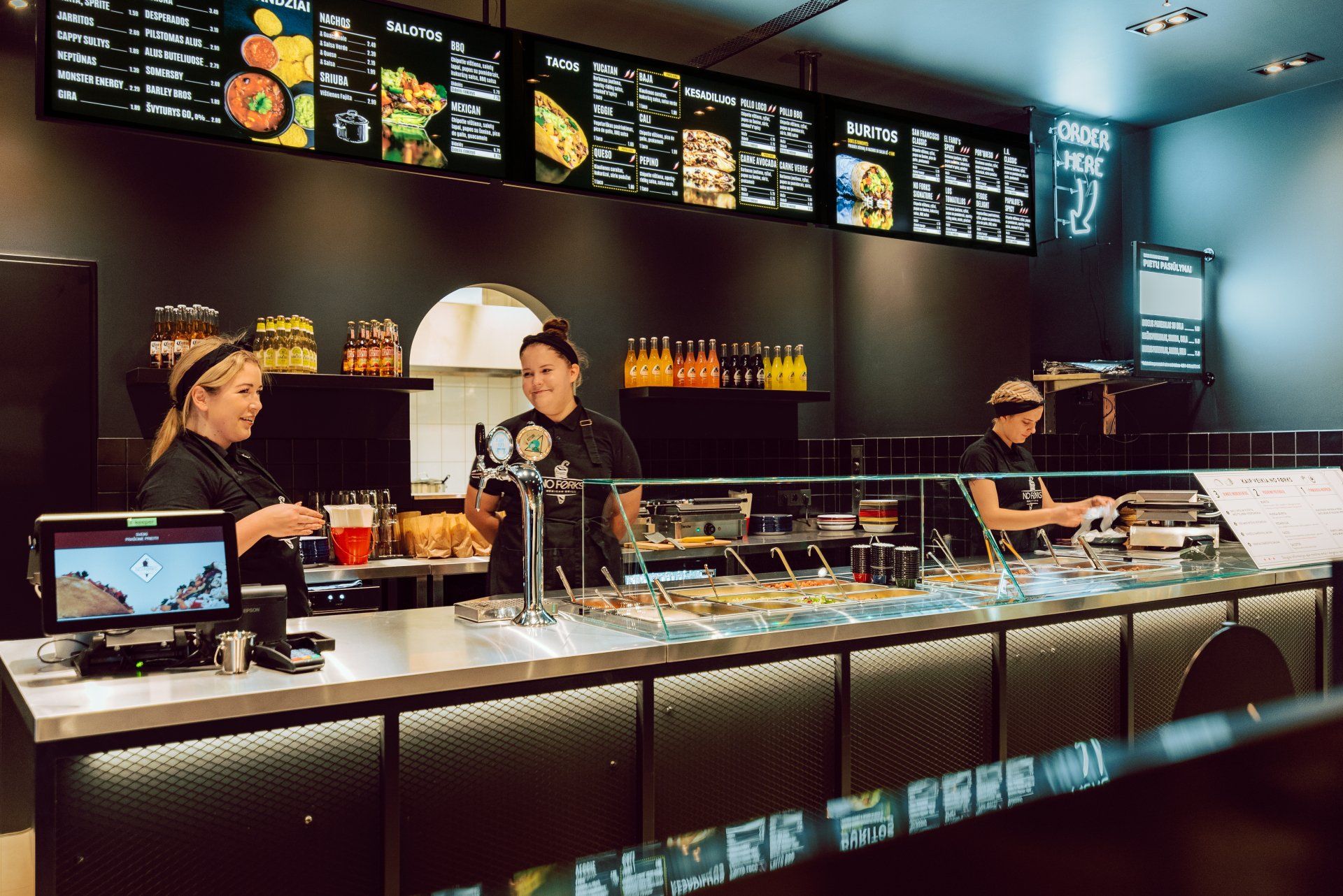 Grupė žmonių, stovinčių už prekystalio restorane.