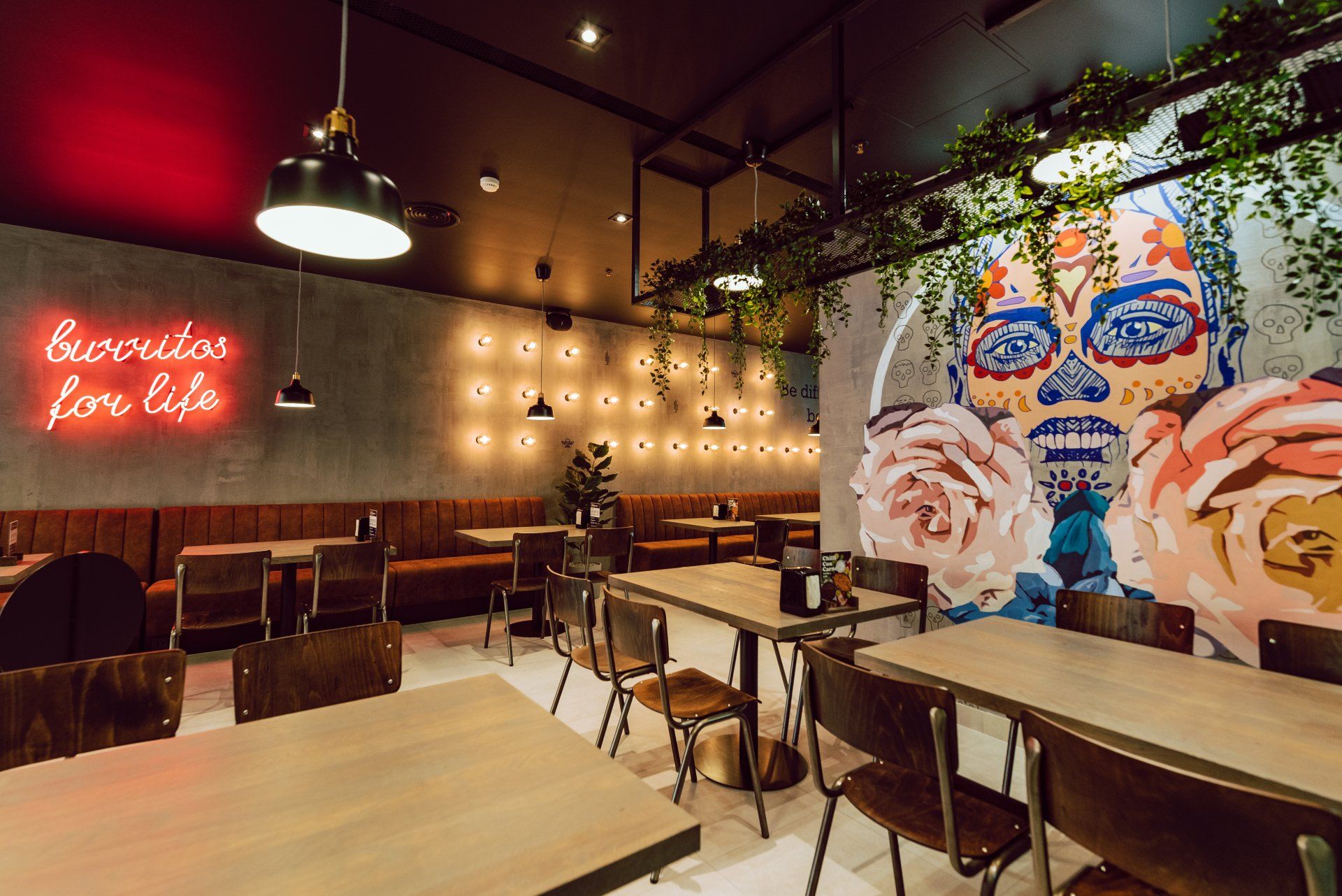 Restoranas su stalais, kėdėmis ir freska ant sienos.