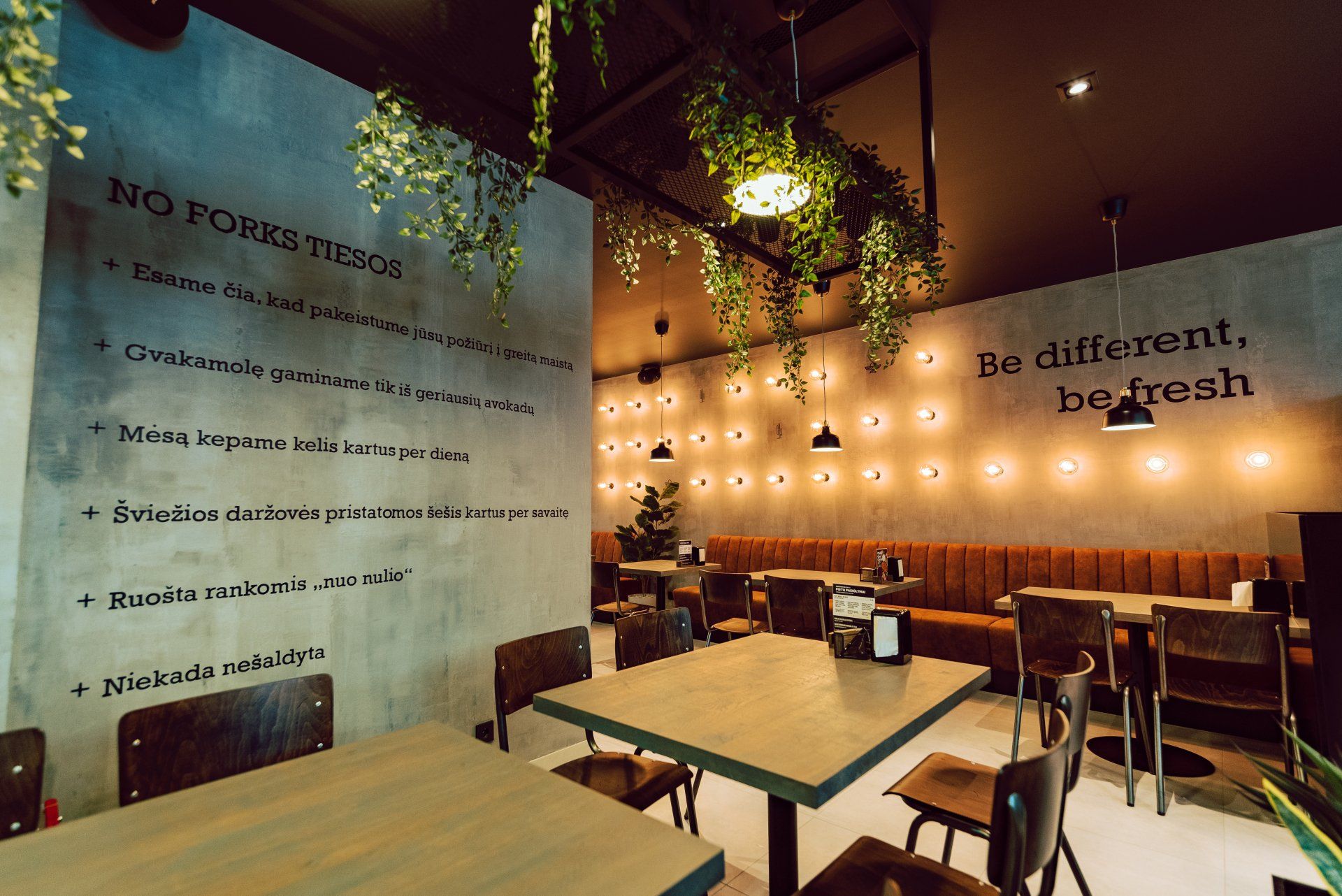 Restoranas su stalais, kėdėmis ir užrašu „būk kitoks, būk šviežias“